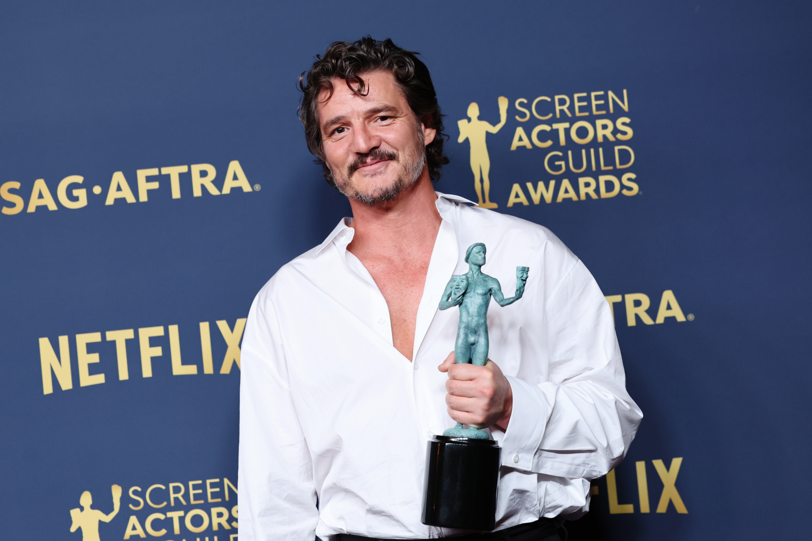 Pedro Pascal w białej koszuli trzyma statuetkę podczas gali Screen Actors Guild Awards.