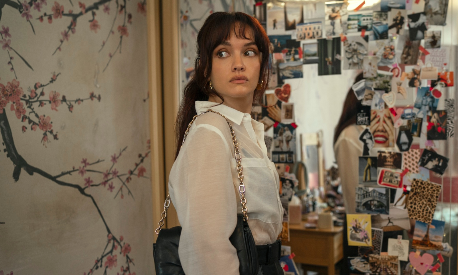 Olivia Cooke w serialu Prime Video „Ta dziewczyna”, stoi przy lustrze otoczona zdjęciami i dekoracjami.