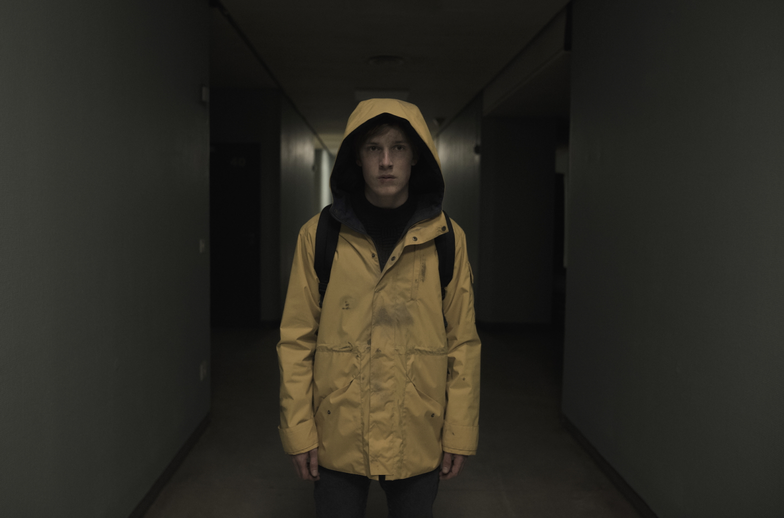 Postać w żółtej kurtce stoi w ciemnym korytarzu, nawiązując do serialu Netflix „Dark”.