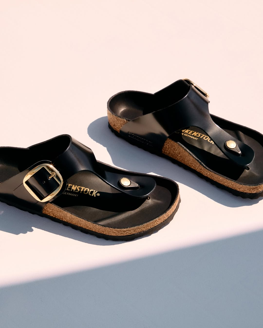 Japonki Birkenstock Gizeh w czarnym kolorze z złotym sprzączką na korkowej podeszwie.
