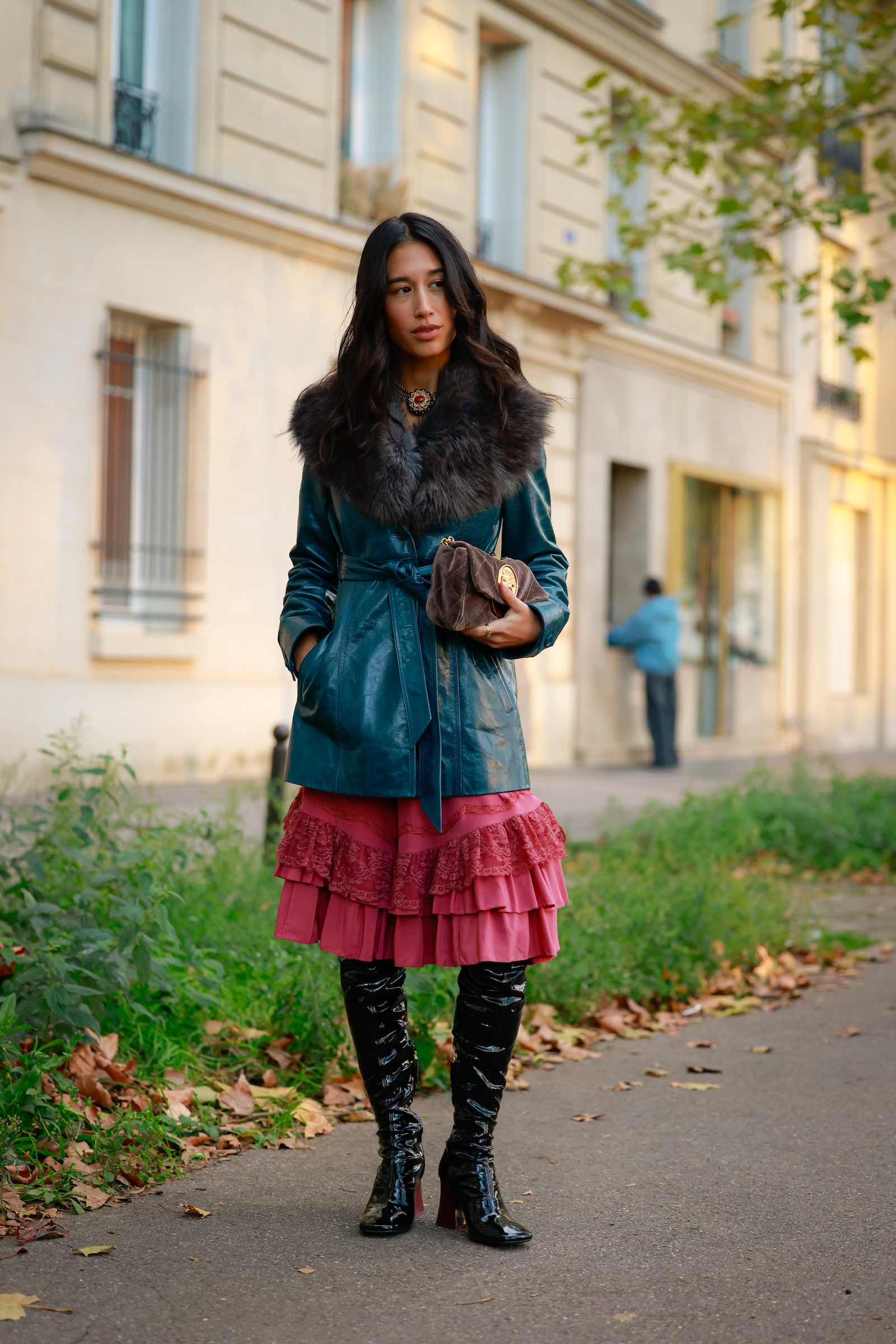 Kobieta w eleganckiej sukience midi w stylu boho, skórzane kozaki za kolano, pozująca na ulicy.
