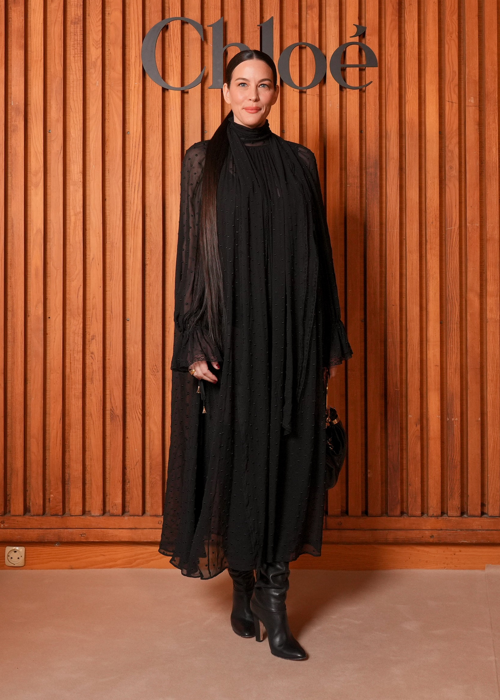 Liv Tyler w maxi sukience boho i wysokich kozakach na obcasie podczas pokazu Chloé na sezon wiosna-lato 2026.