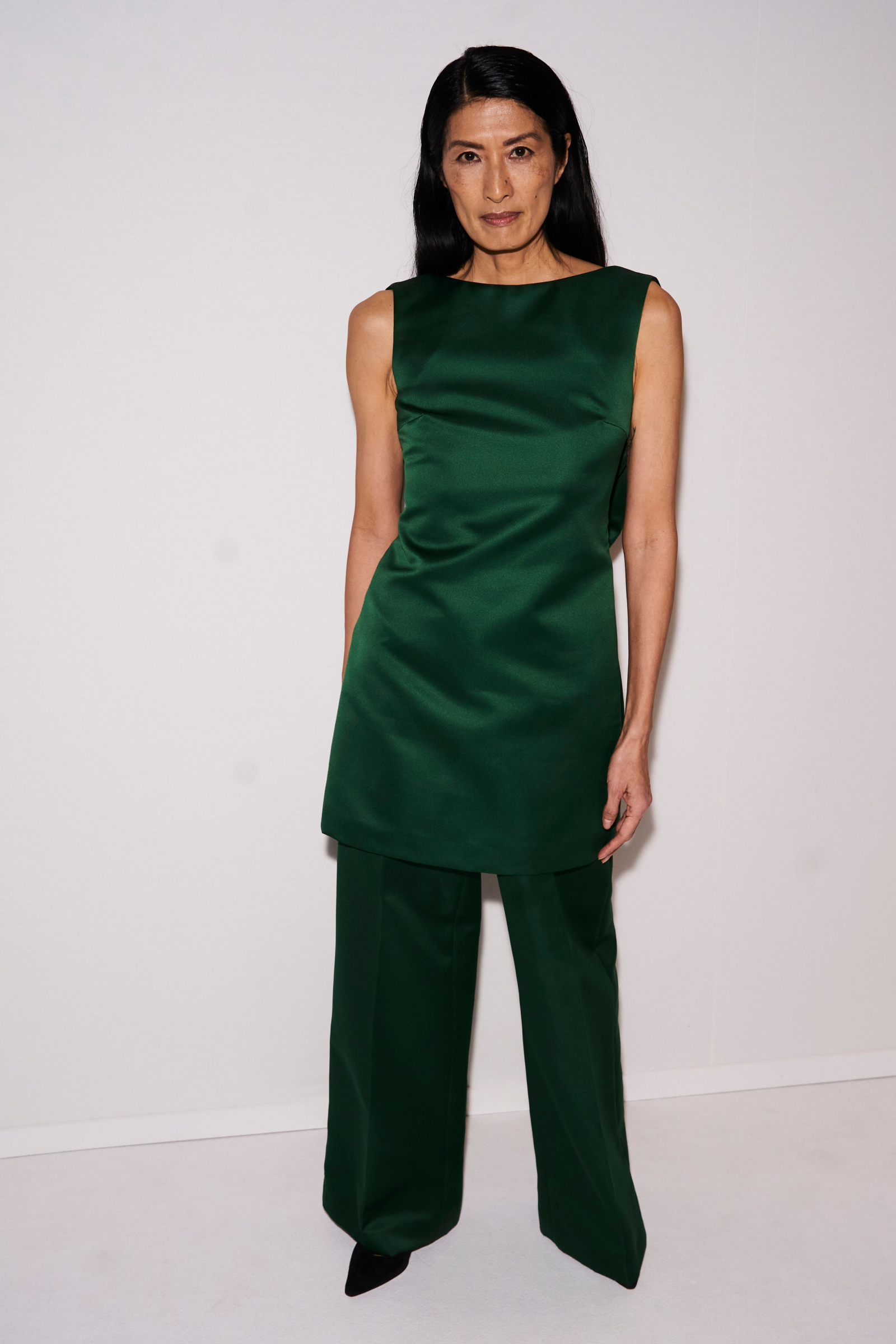 Suzi de Givenchy w eleganckiej tunice i spodniach palazzo w intensywnym zielonym kolorze.