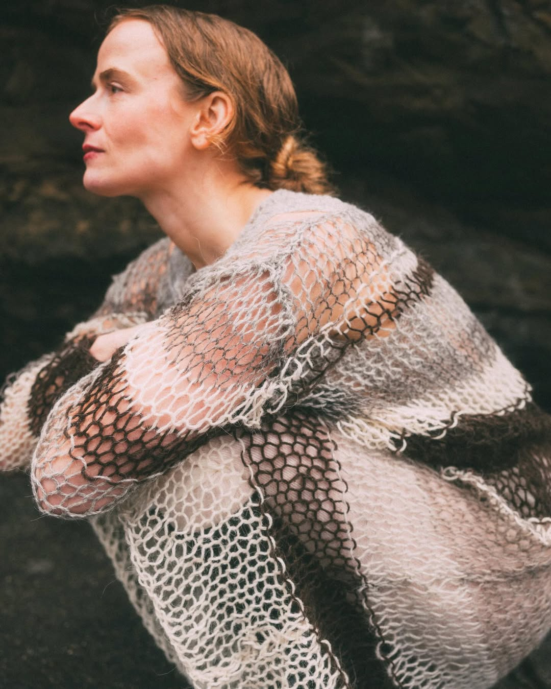 Dziergany sweter damski marki Guðrun & Guðrun w odcieniach beżu i brązu, modelka w stylowej pozycji.