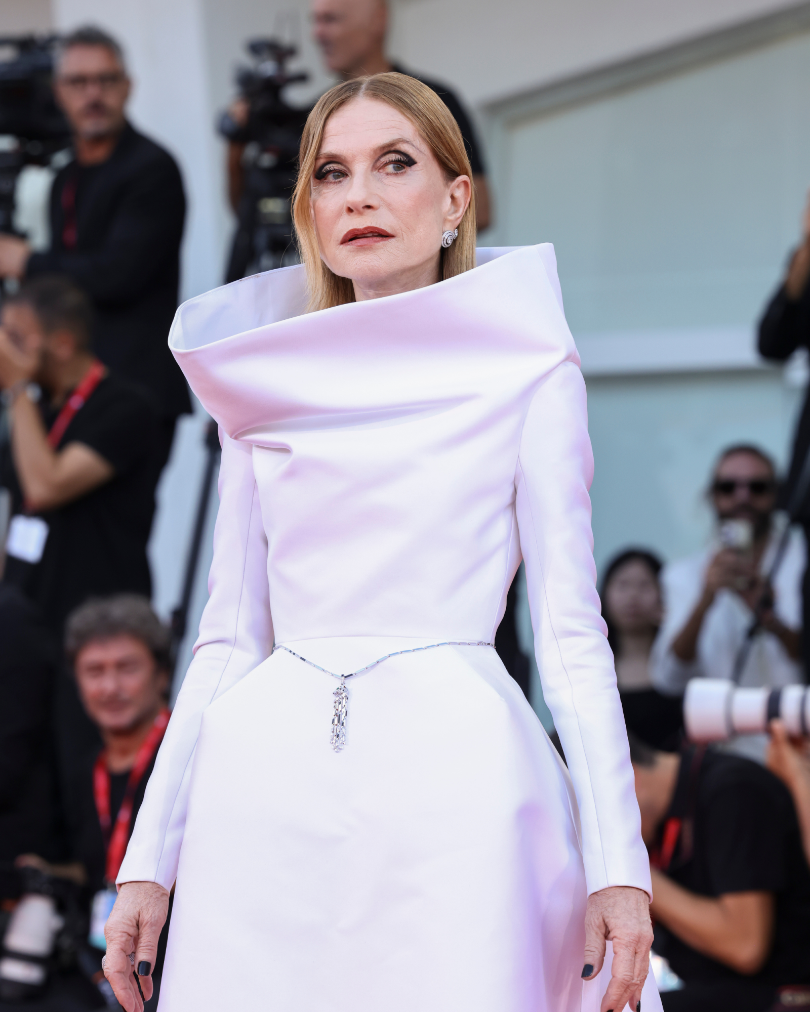 Francuska aktorka Isabelle Huppert w eleganckiej, białej sukni z oryginalnym kołnierzem na czerwonym dywanie.