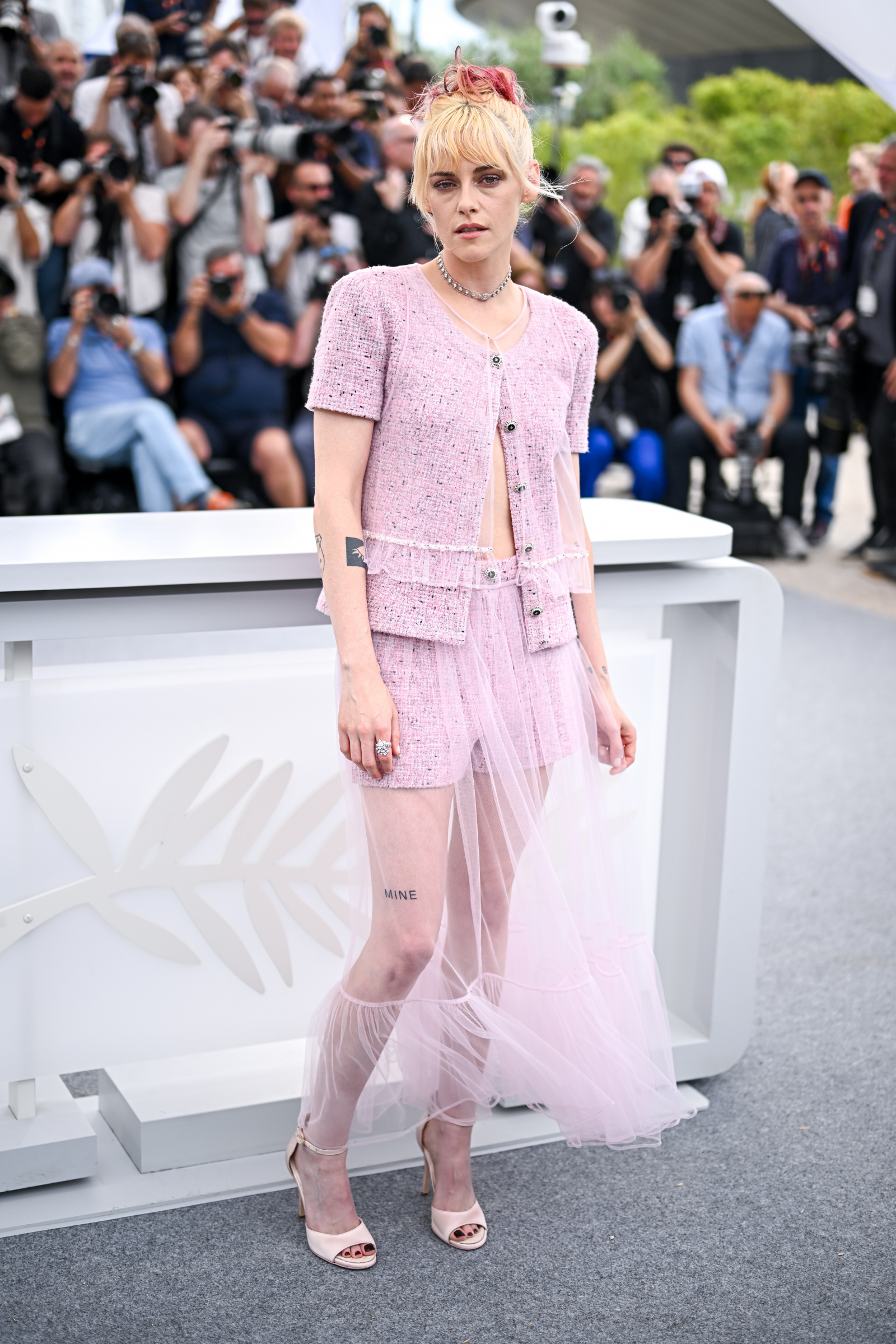 Kristen Stewart w długiej spódnicy tiulowej Chanel, na tle fotograficznego tłumu podczas wydarzenia.