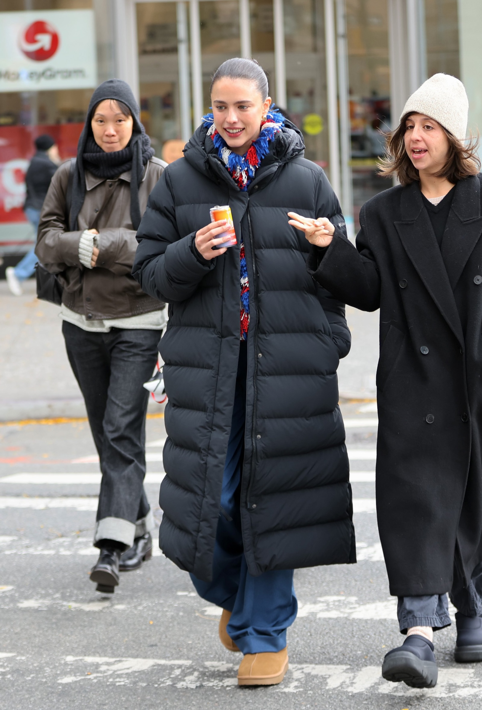 Margaret Qualley w długiej puchowej czarnej kurtce damskiej, niebieskich spodniach i krótkich butach Ugg, spaceruje z przyjaciółkami.