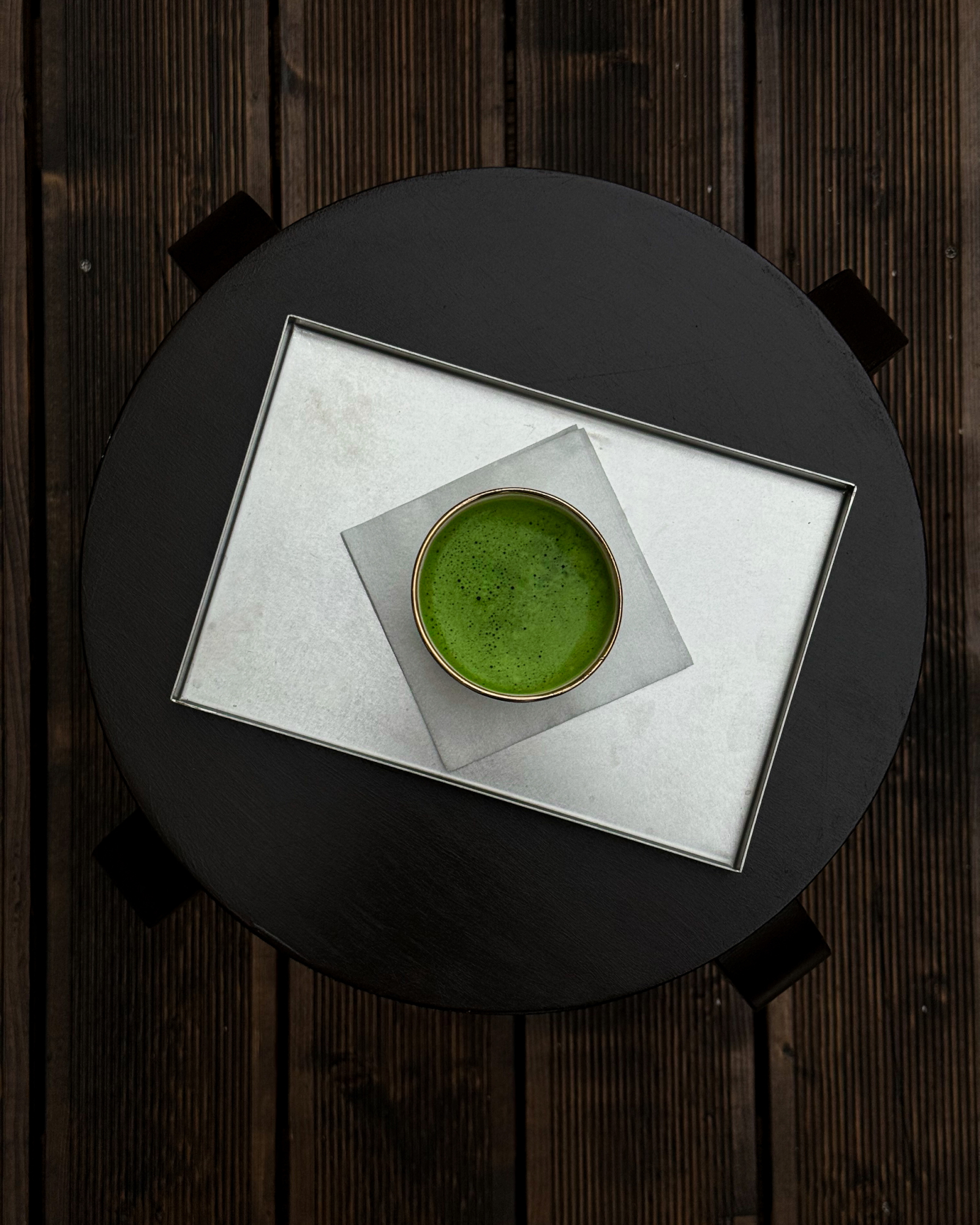Matcha na tacy w kawiarni Café Fourteen, podana na czarnym stole z drewnianą podłogą.