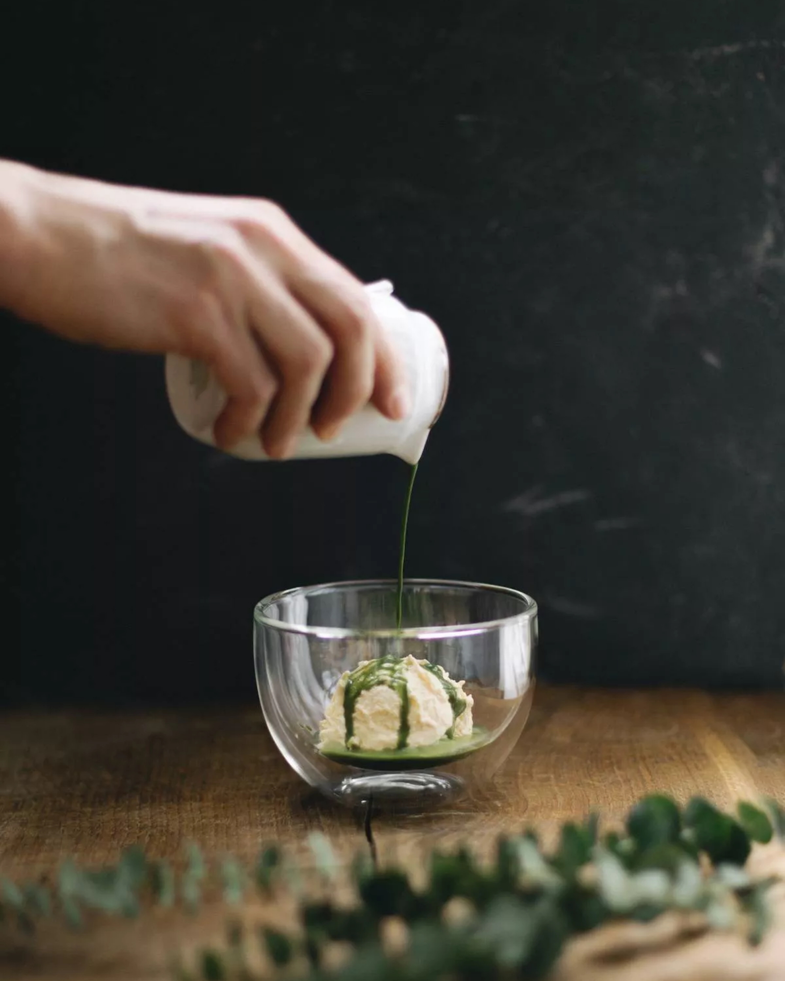 W Moya Matcha Bar ktoś polewa lody zieloną matchą w przezroczystej miseczce.