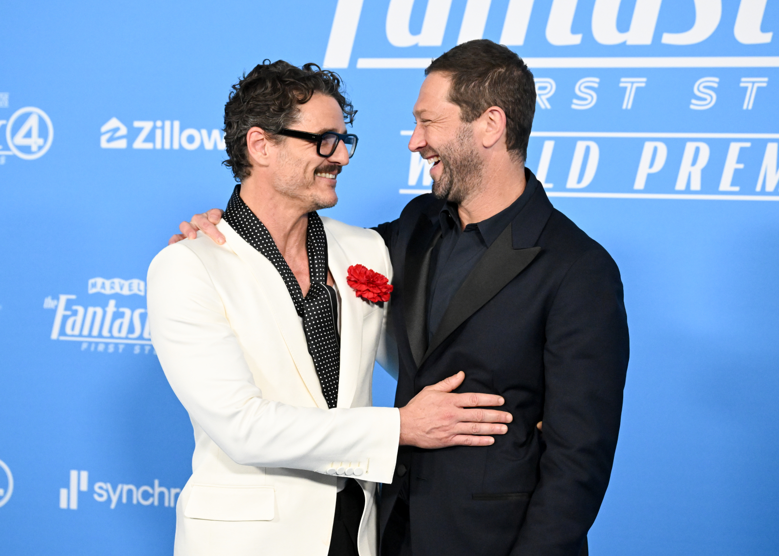 Pedro Pascal i Ebon Moss-Bachrach na premierze filmu „Fantastyczna 4: Pierwsze kroki”, świętujący razem na niebieskim tle.