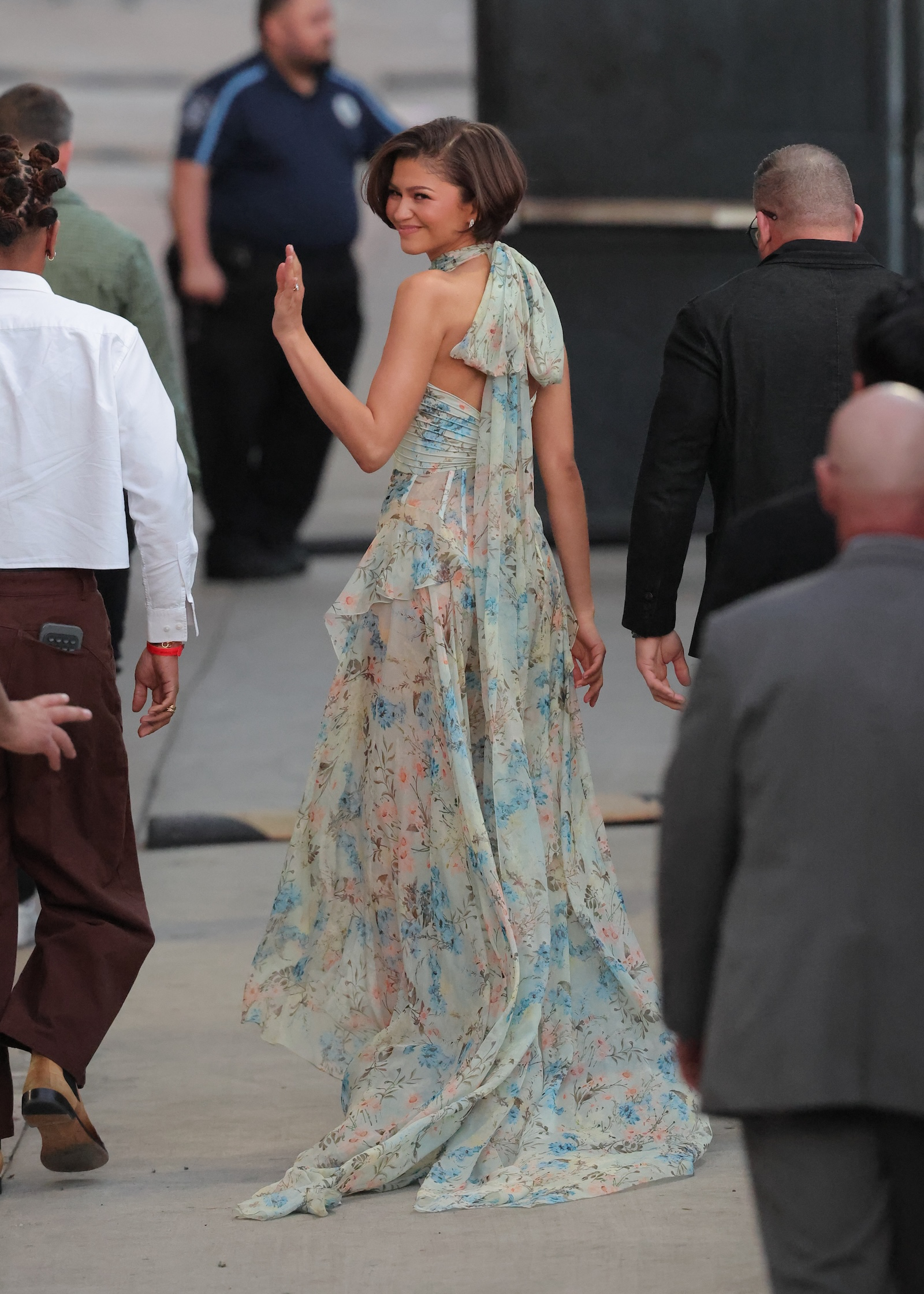 Zendaya w zwiewnej, kwiecistej sukni na wydarzeniu w 2026 roku, odwraca się z uśmiechem do kamer.