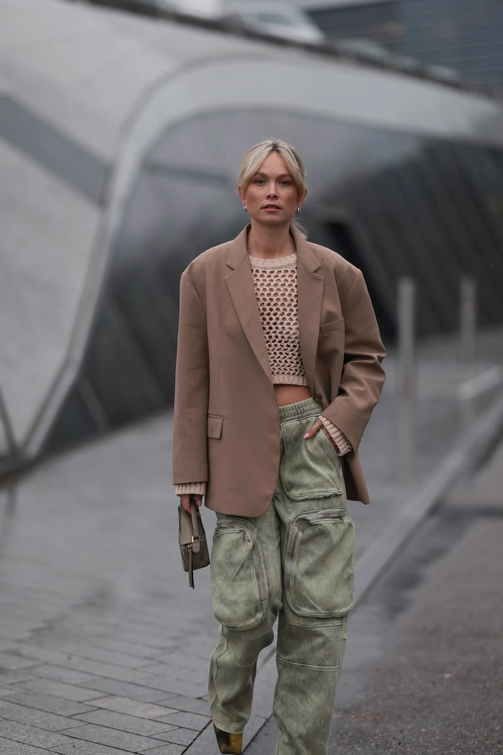 Beżowa szydełkowa bluzka, beżowa marynardka, zielone jeansy bojówki. Modny, miejskiego stylu look.