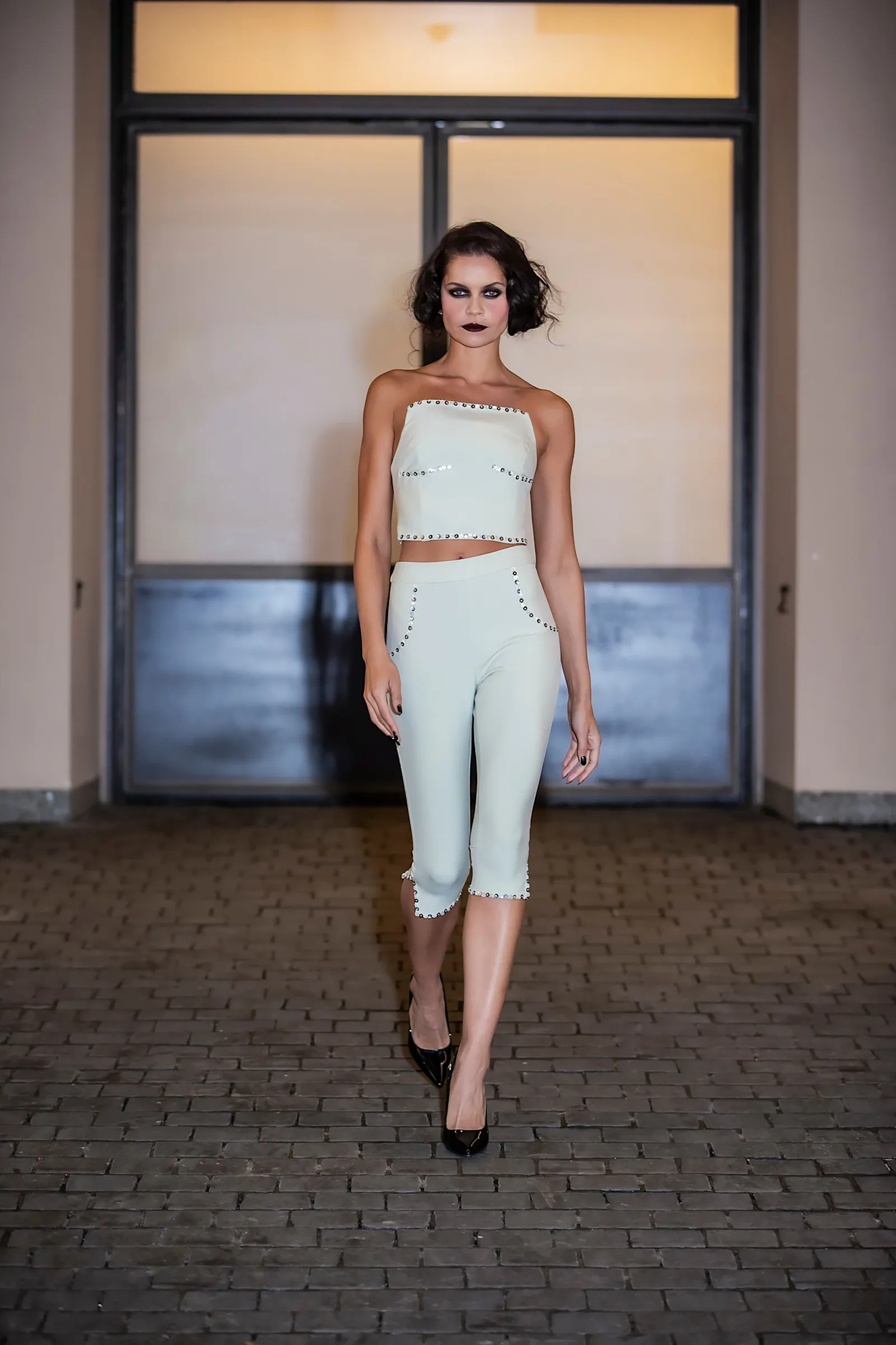 Modelka w białym, dopasowanym topie i bermudach.