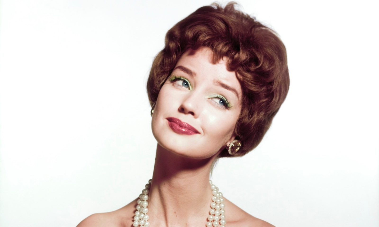 Modelka w eleganckim makijażu z zielonymi akcentami, na łamach magazynu Vogue z 1959 roku.
