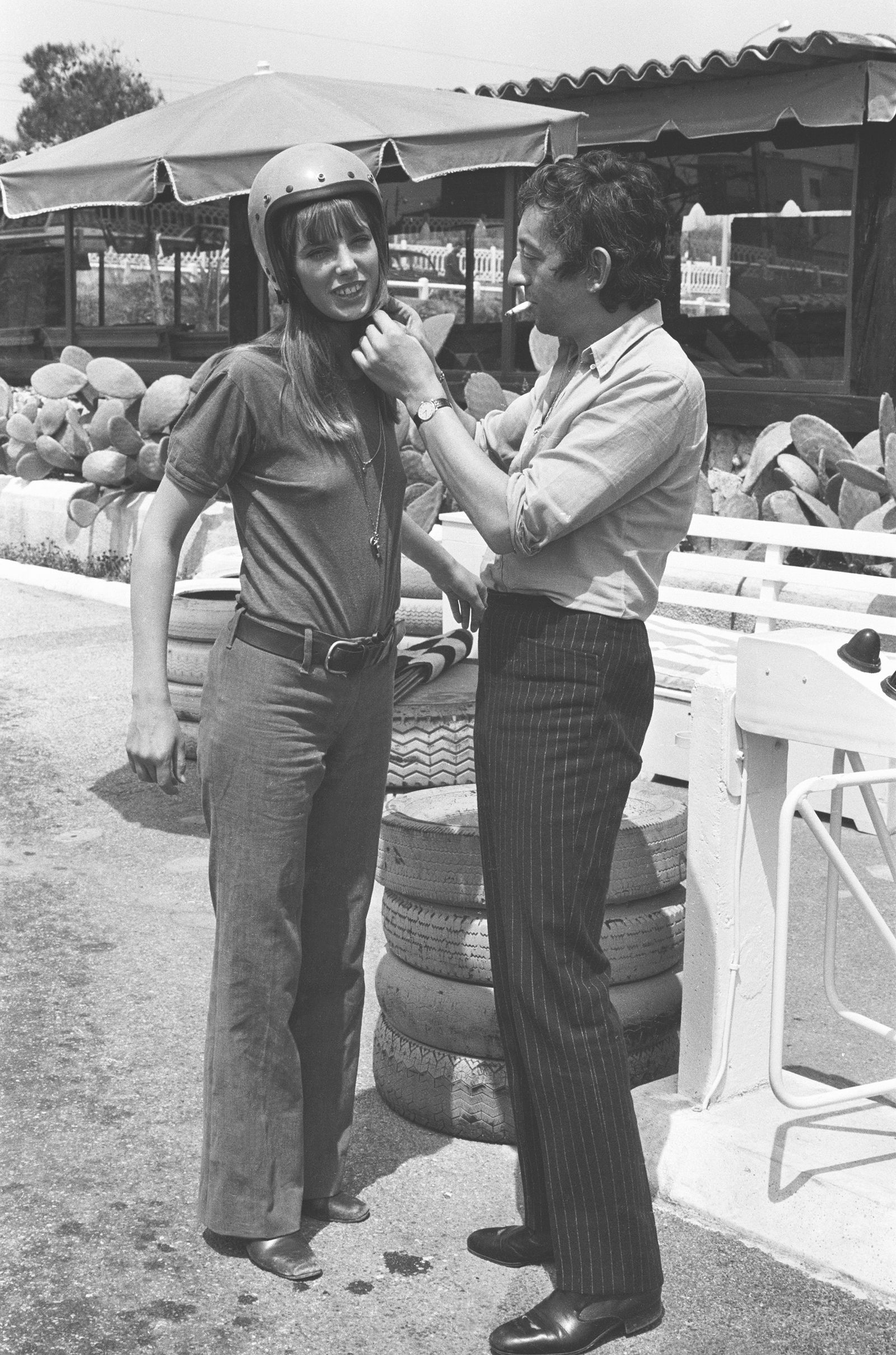Jane Birkin w botkach z kwadratowym noskiem, rozszerzanych jeansach, białym tshircie zakłada kask 