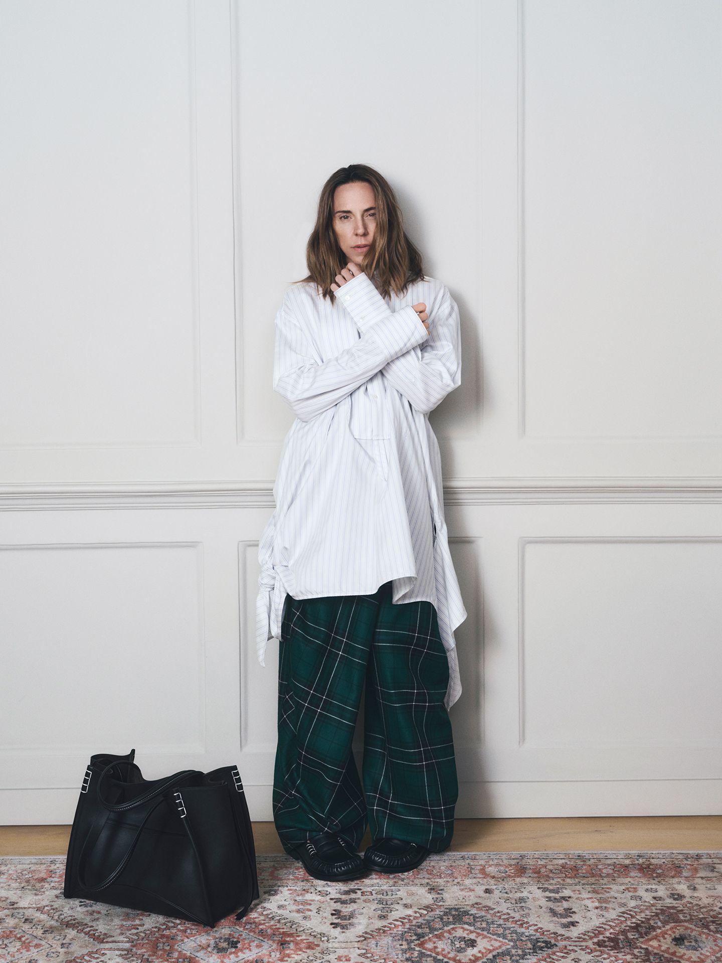 Mel C w oversize'owej, białej koszuli w paski i w spodniach w kratę oraz z czarną torebką w kampanii JW Andersona