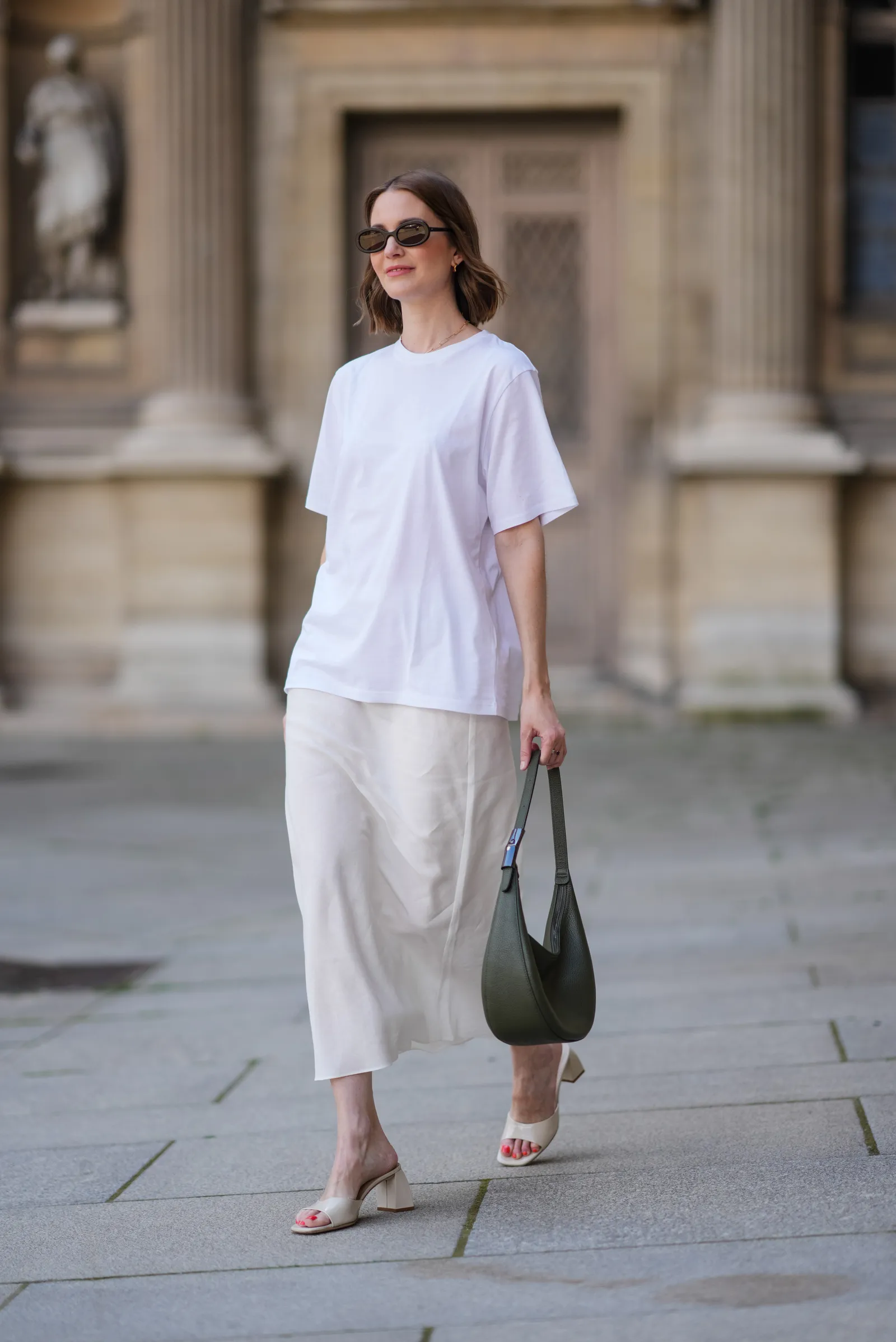 Street style pokazuje, jak w sezonie wiosna–lato 2025 wyglądać elegancko w lnianych spódnicach midi i klapkach na obcasie.
(Fot. Edward Berthelot / Getty Images)