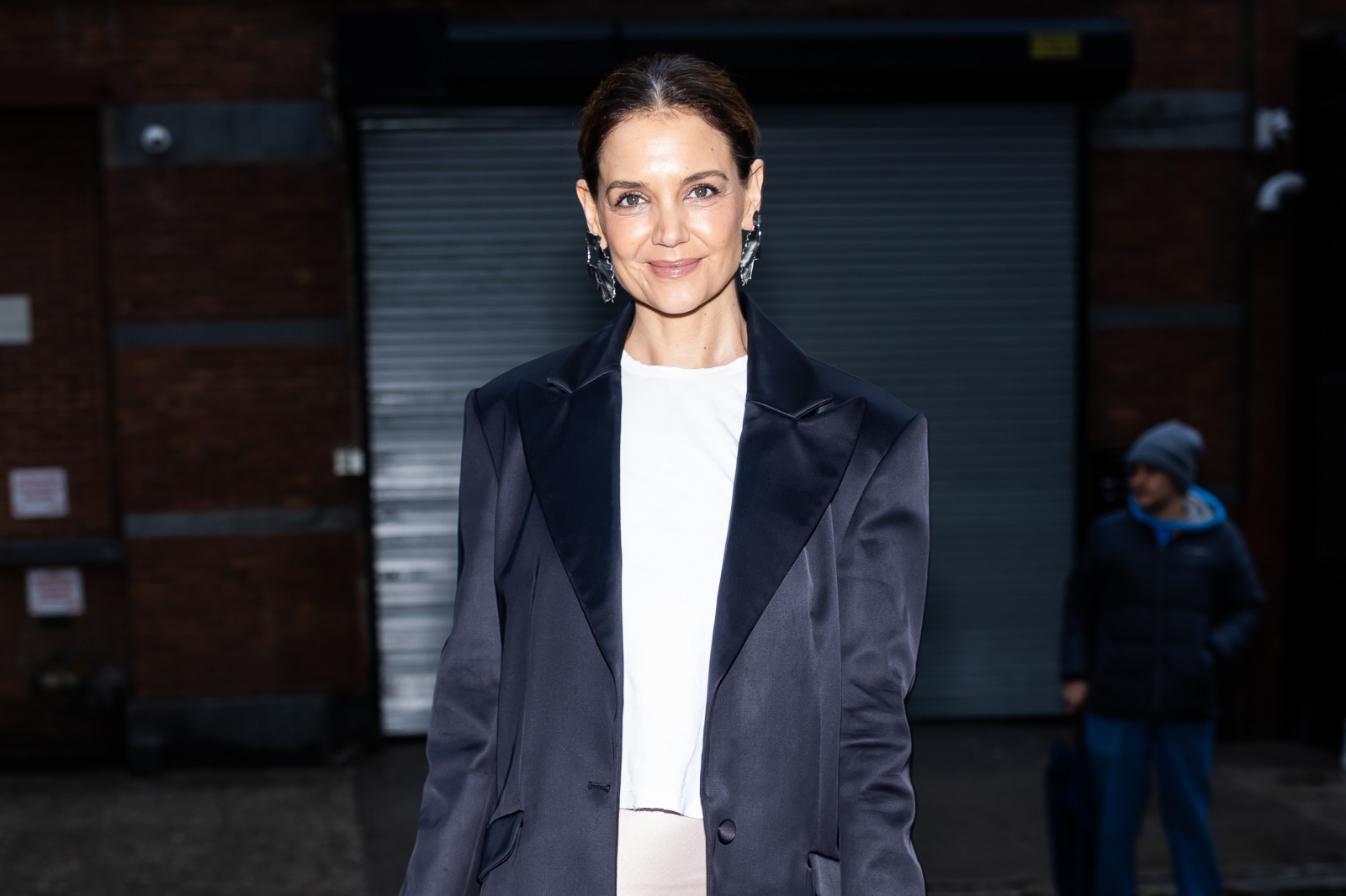 Katie Holmes w białym topie i połyskującej, ciemnogranatowej marynarce pozuje na ulicy Nowego Jorku.