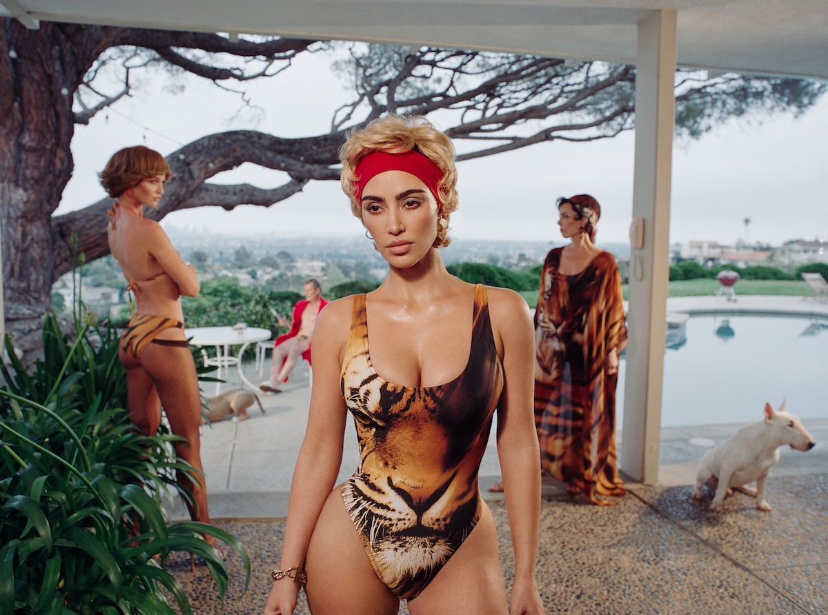 Kim Kardashian w kostiumie kąpielowym w kampanii marek Skims i Roberto Cavalli, z tłem basenu i innymi modelkami.