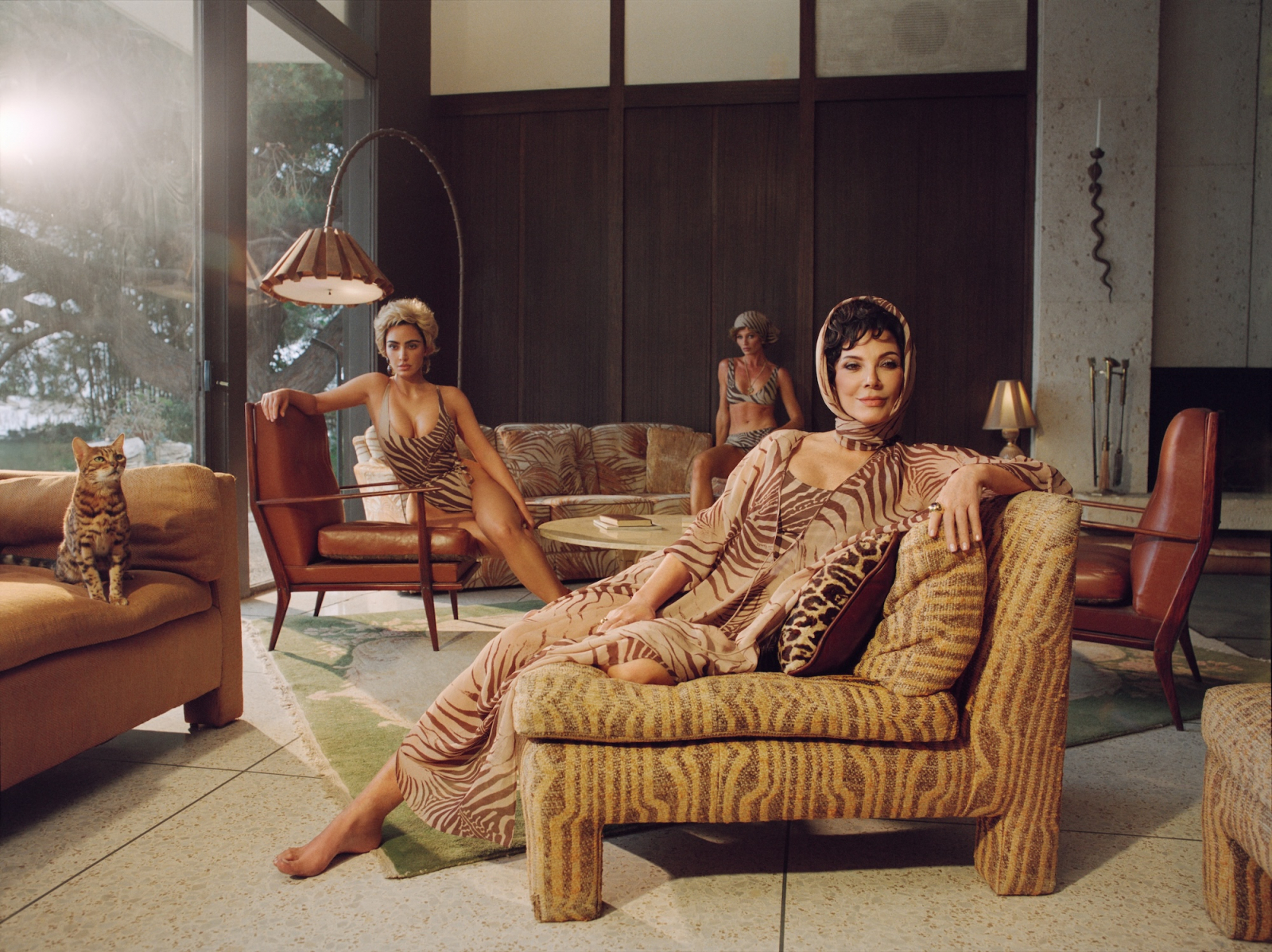Kim Kardashian i Kris Jenner w kampanii marek Skims i Roberto Cavalli, siedzą na stylowych sofach w eleganckim wnętrzu.
