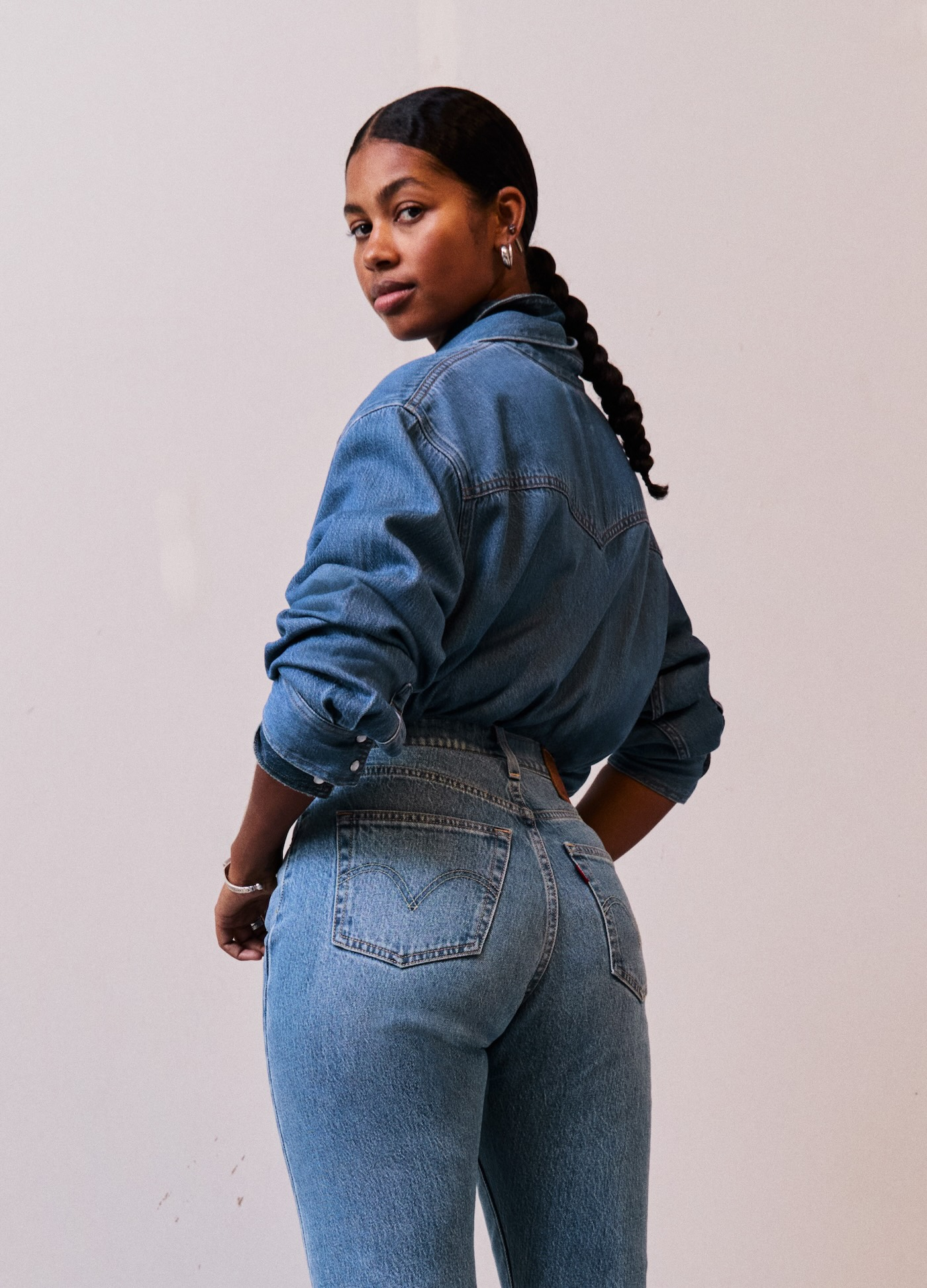 Modelka w jeansach damskich Levi's 501 Curve i jeansowej koszuli pozuje na białym tle.