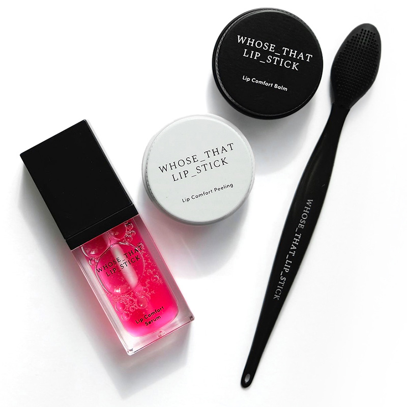 Na zdjęciu znajdują się kosmetyki do ust: różowy serum, peeling oraz balsam &quot;Whose That Lip Stick&quot;, obok szczoteczka do ust.