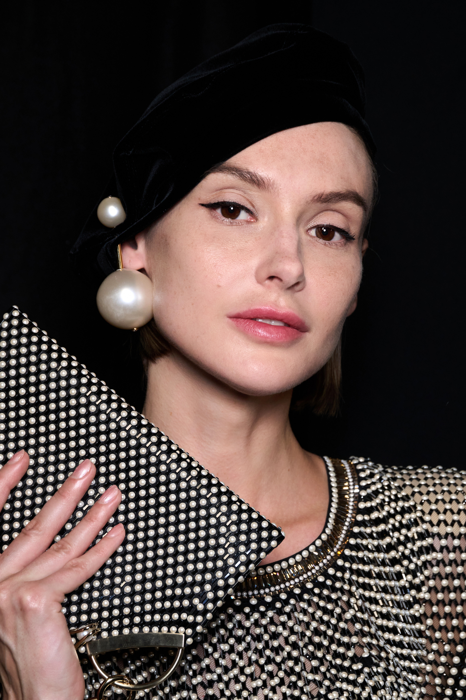 Modelka z szampańskim manicure trzyma elegancką torebkę, wygląda stylowo i szykownie, idealna na zaręczyny.