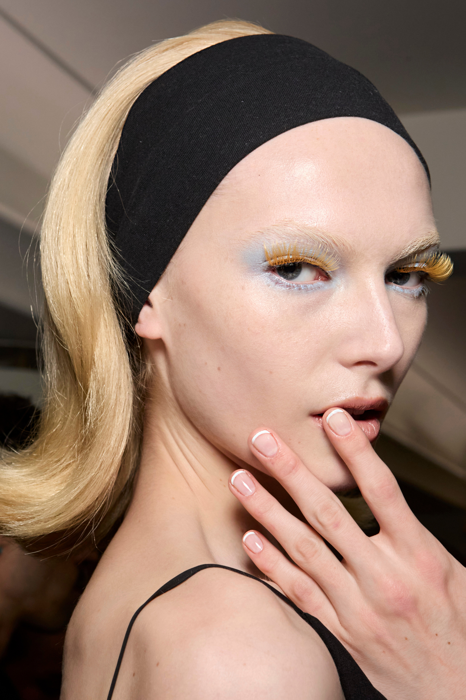 Modelka z fryzurą w stylu retro, prezentująca ślubny french manicure na zaręczyny oraz wyrazisty makijaż oczu.