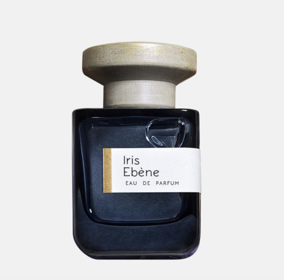 Butelka perfum w ciemnoniebieskim kolorze z metalową, złotą nakrętką. Etykieta z napisem "Iris Ebène Eau de Parfum".