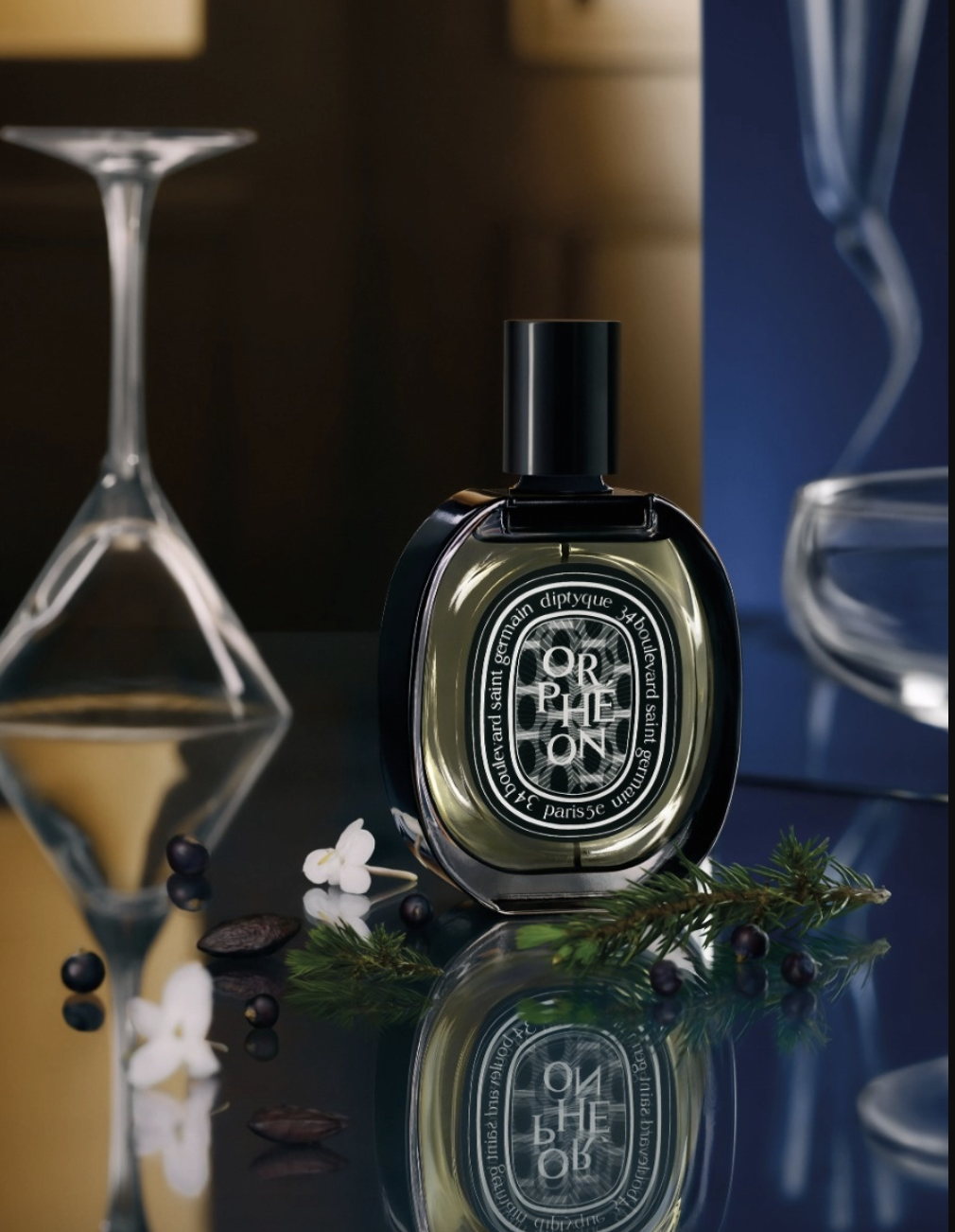 Flakon perfum Orphéon na eleganckim tle, z dodatkiem kwiatów, jagód i innych naturalnych elementów.
