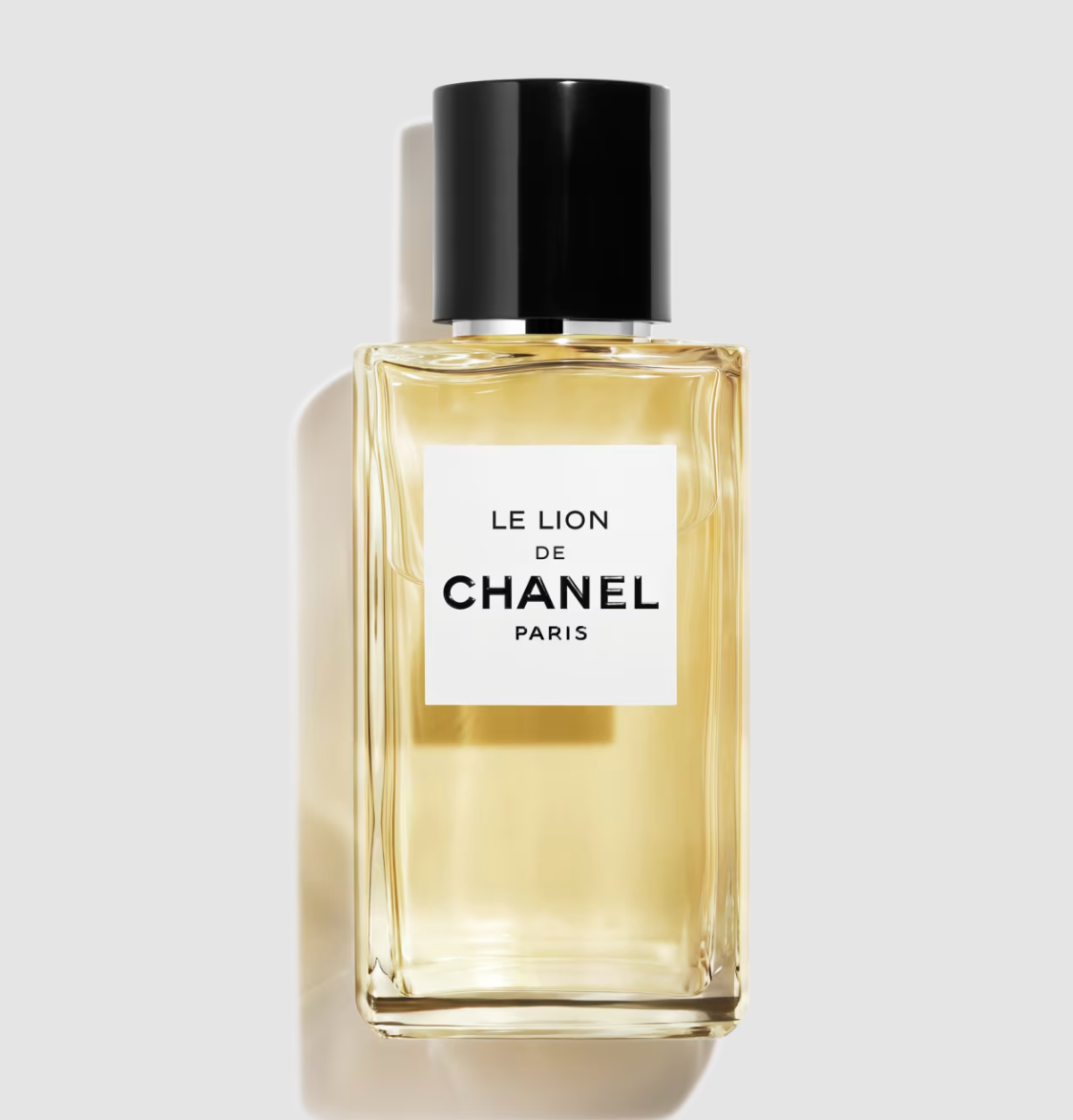 Flakon perfum "Le Lion de Chanel" z przezroczystego szkła, etykieta z napisem w czerni na białym tle.