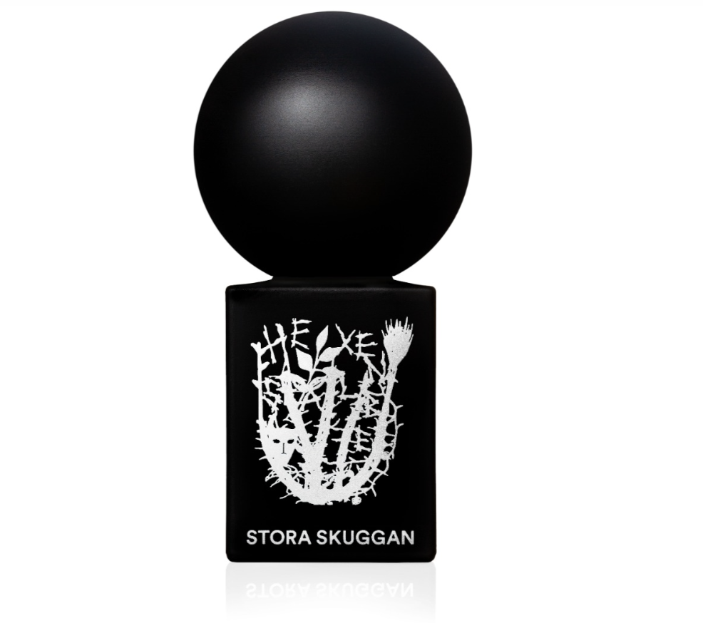 Czarna butelka perfum z okrągłą nakrętką i białym, artystycznym logo "STORA SKUGGAN".
