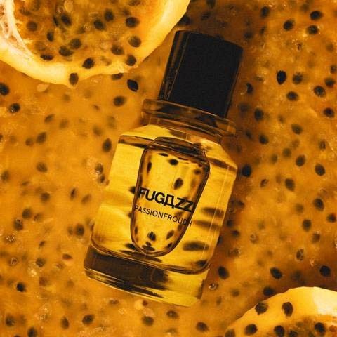 Perfumy na jesień w butelce Fugazzi Passionfruits, otoczone połówkami owoców marakui w ciepłych kolorach.