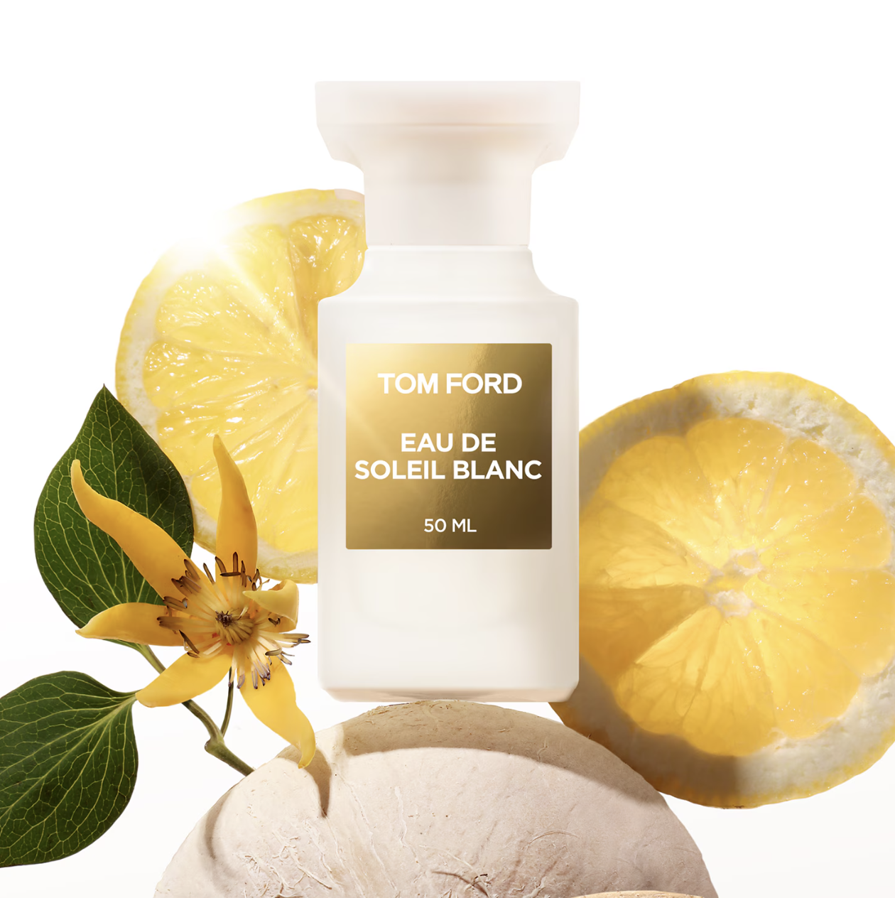 Perfumy pachnące jak dzień na plaży: Flakon perfum Tom Ford "Eau de Soleil Blanc" otoczony cytrynami i zielonymi liśćmi.