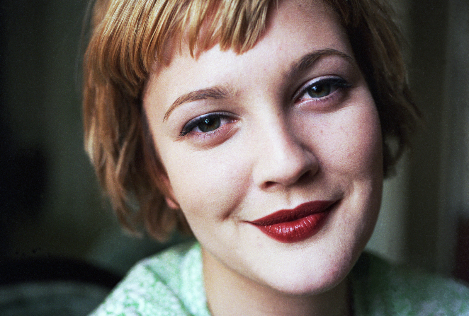Drew Barrymore z lat 90. z kr&oacute;tkimi włosami i charakterystycznymi czerwonymi ustami.