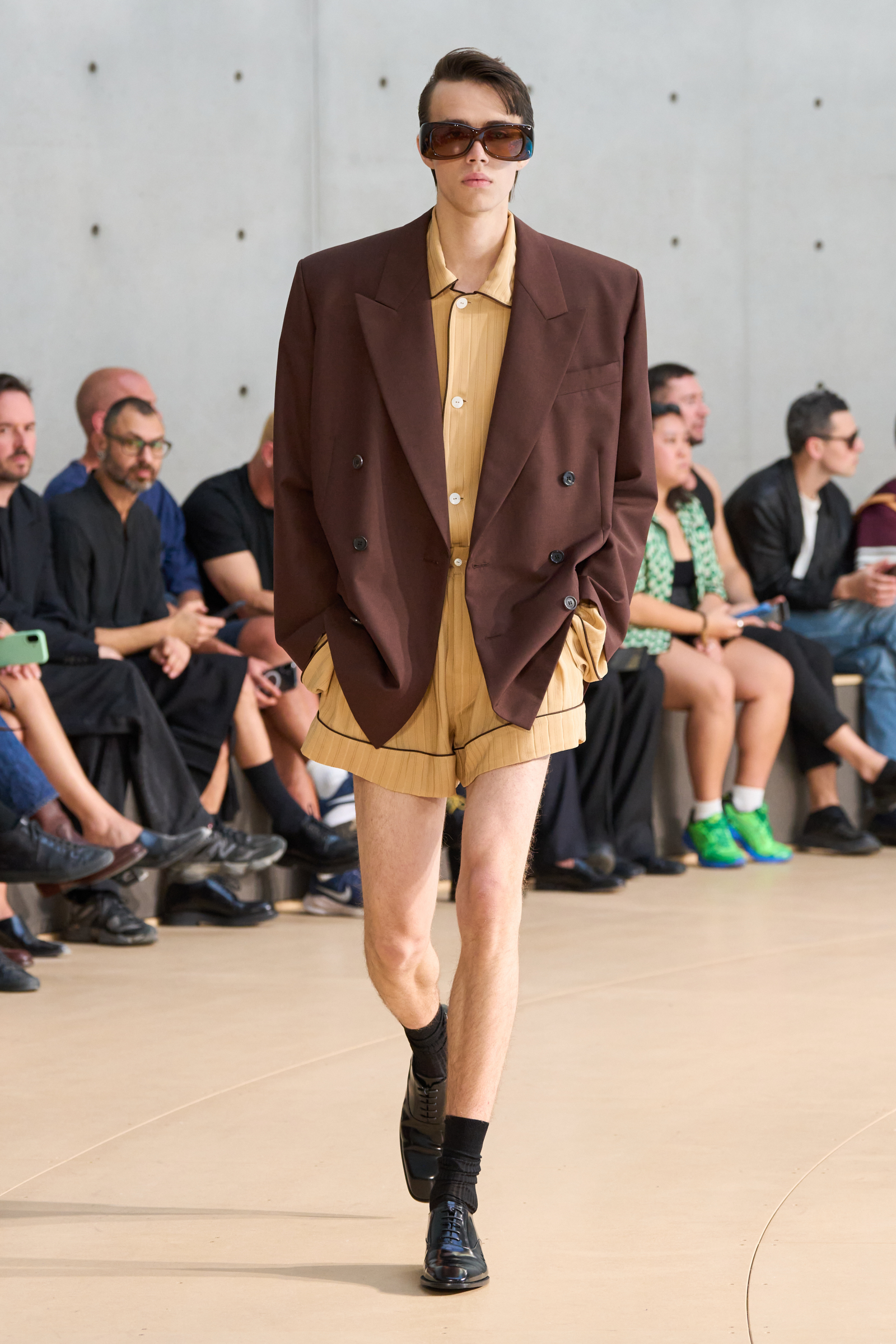 Model w męsko-damskim stroju na pokazie Saint Laurent wiosna-lato 2026, noszący krótkie spodenki znane jako puldry i elegancki styl.