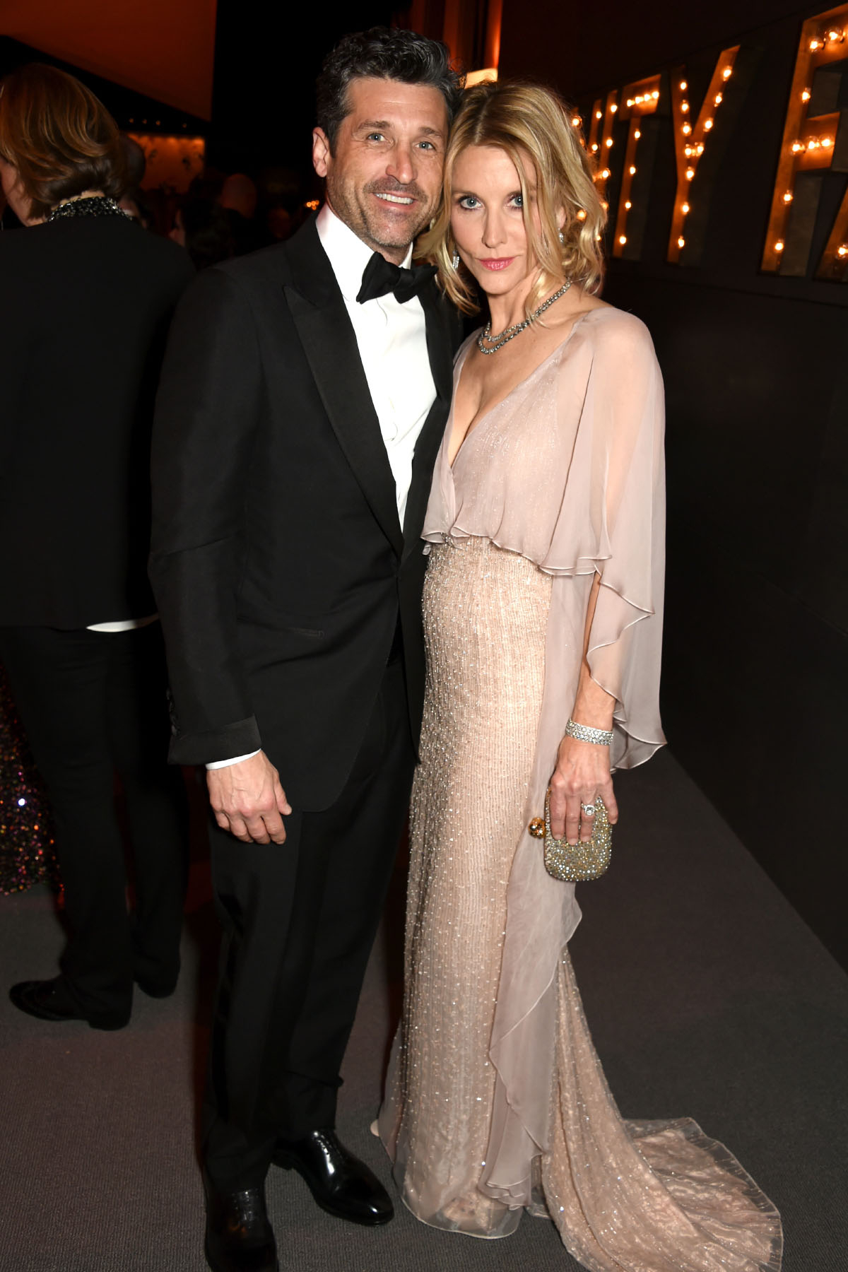 Jillian Fink i Patrick Dempsey pozują razem na eleganckim wydarzeniu, ubrani w stylowe kreacje wieczorowe.