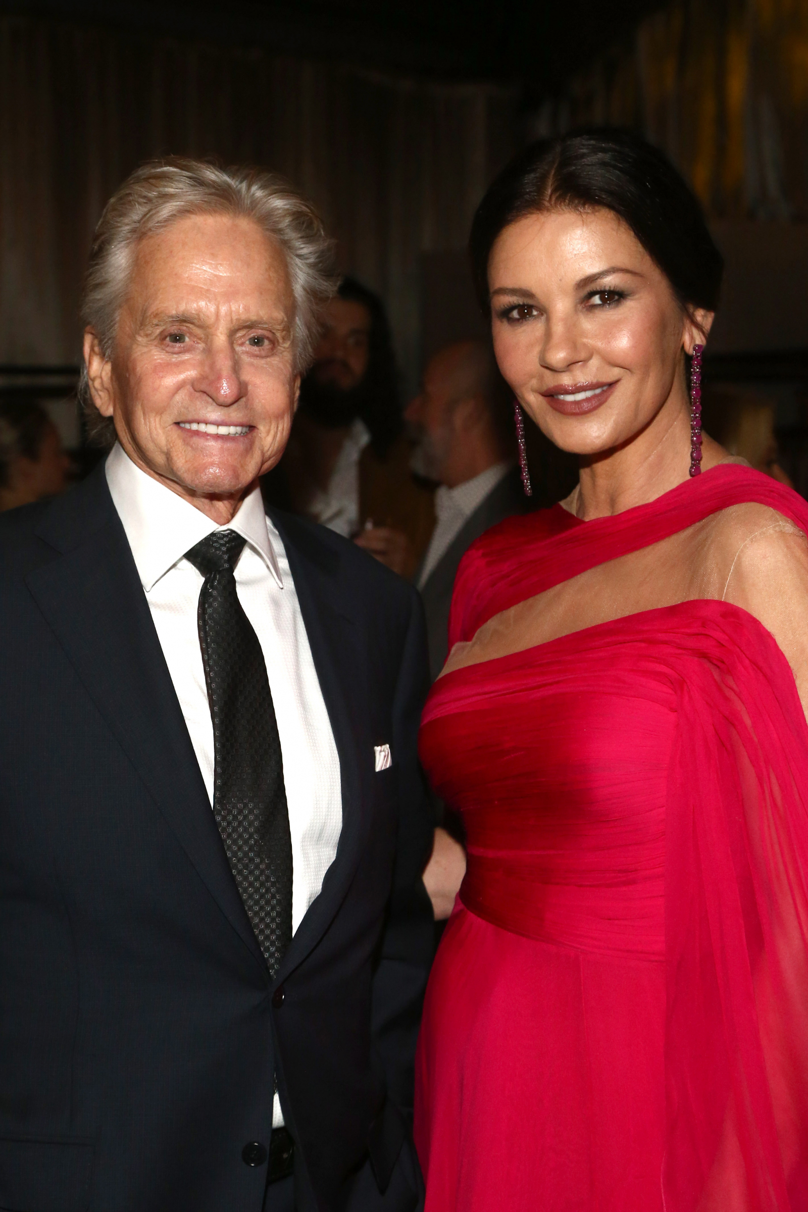 Michael Douglas z żoną Catherine Zeta-Jones na wydarzeniu Netflix w 2019 roku, uśmiechnięci w eleganckich strojach.
