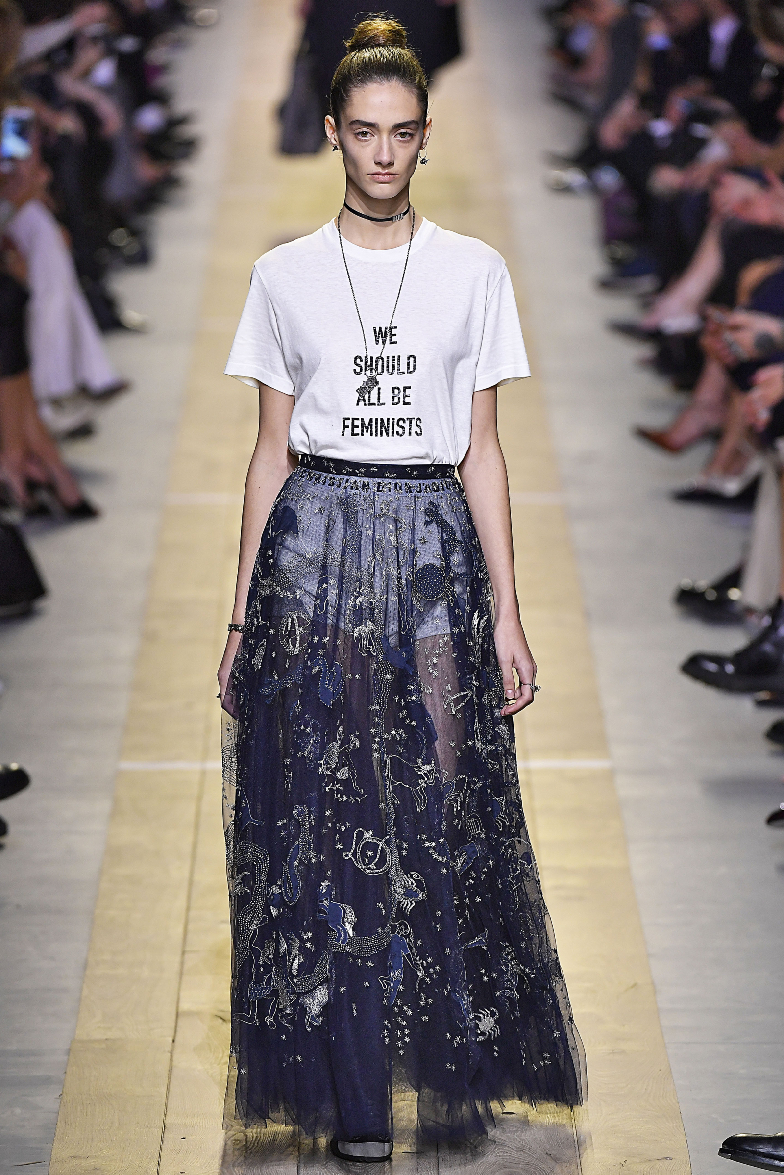 Modelka prezentuje T-shirt feministyczny Dior z cytatem będącym tytułem eseju Chimamandy Ngozi Adichie, uzupełniony elegancką, długą spódnicą.