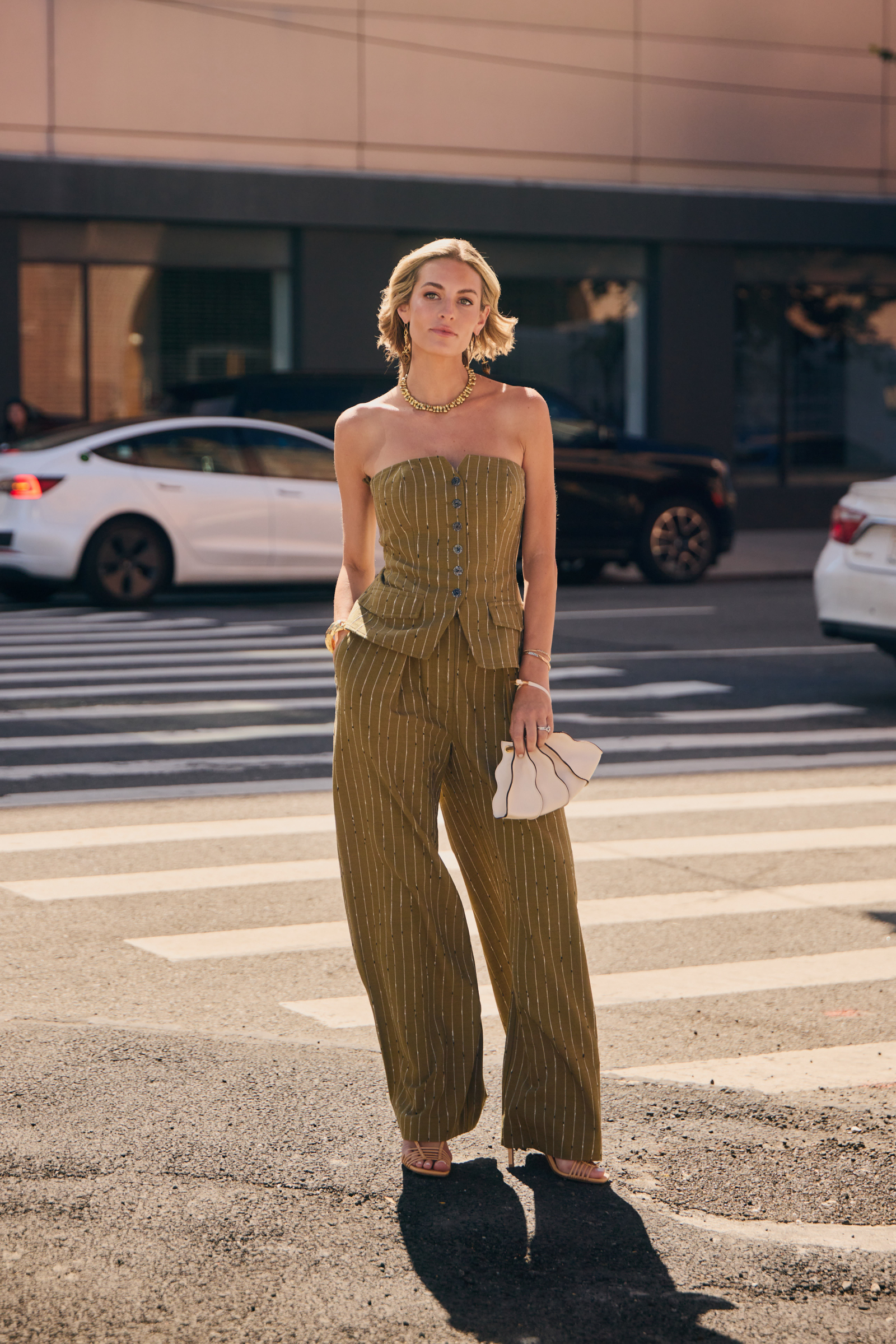 Komplet w odcieniu khaki z gorsetem i eleganckimi spodniami, dodatkami i stylowymi sandałami, prezentujący modny look.