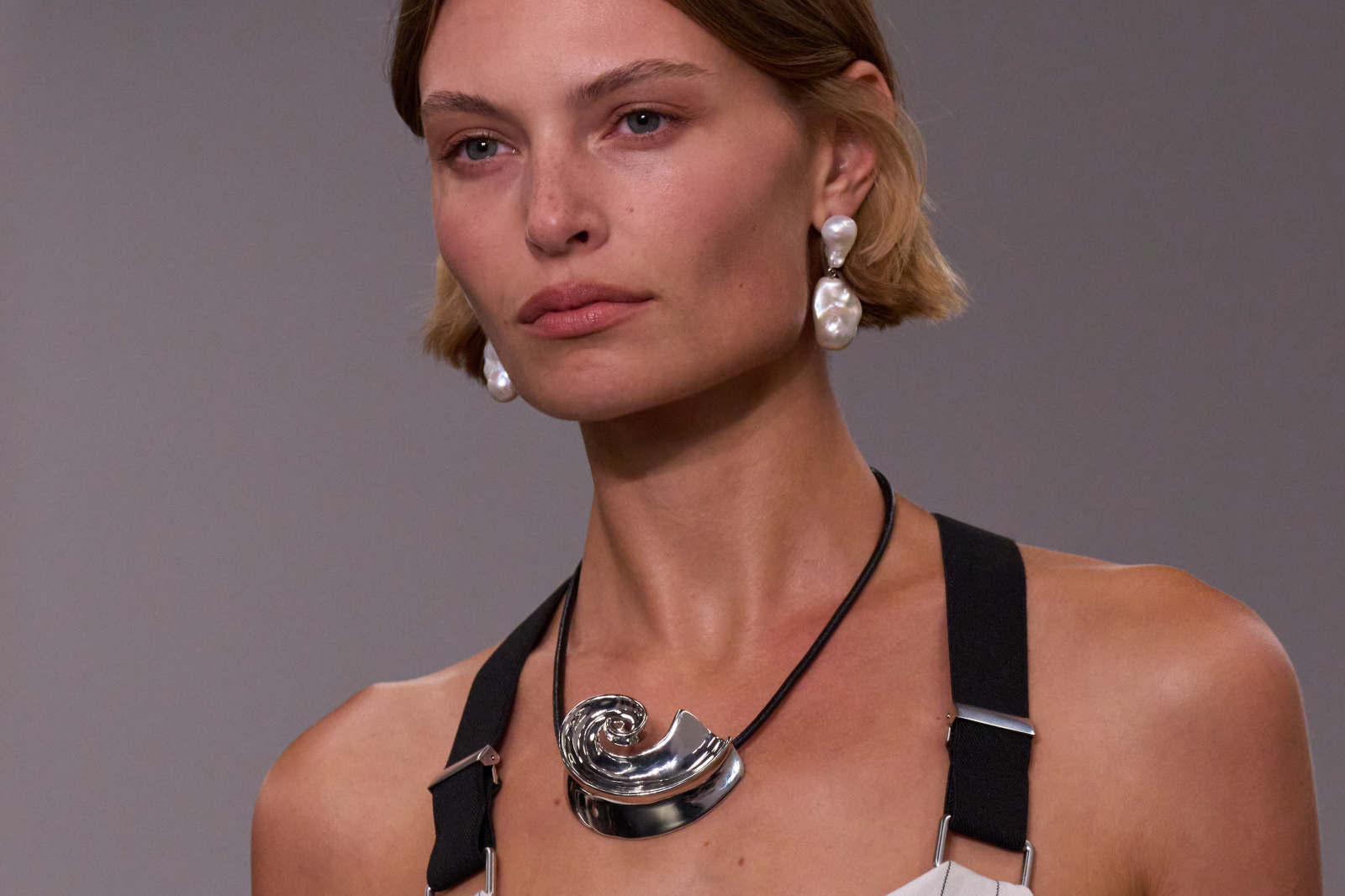 Modelka prezentująca biżuterię na pokazie Ralph Lauren wiosna 2026, z wyrafinowanym naszyjnikiem i dużymi kolczykami.