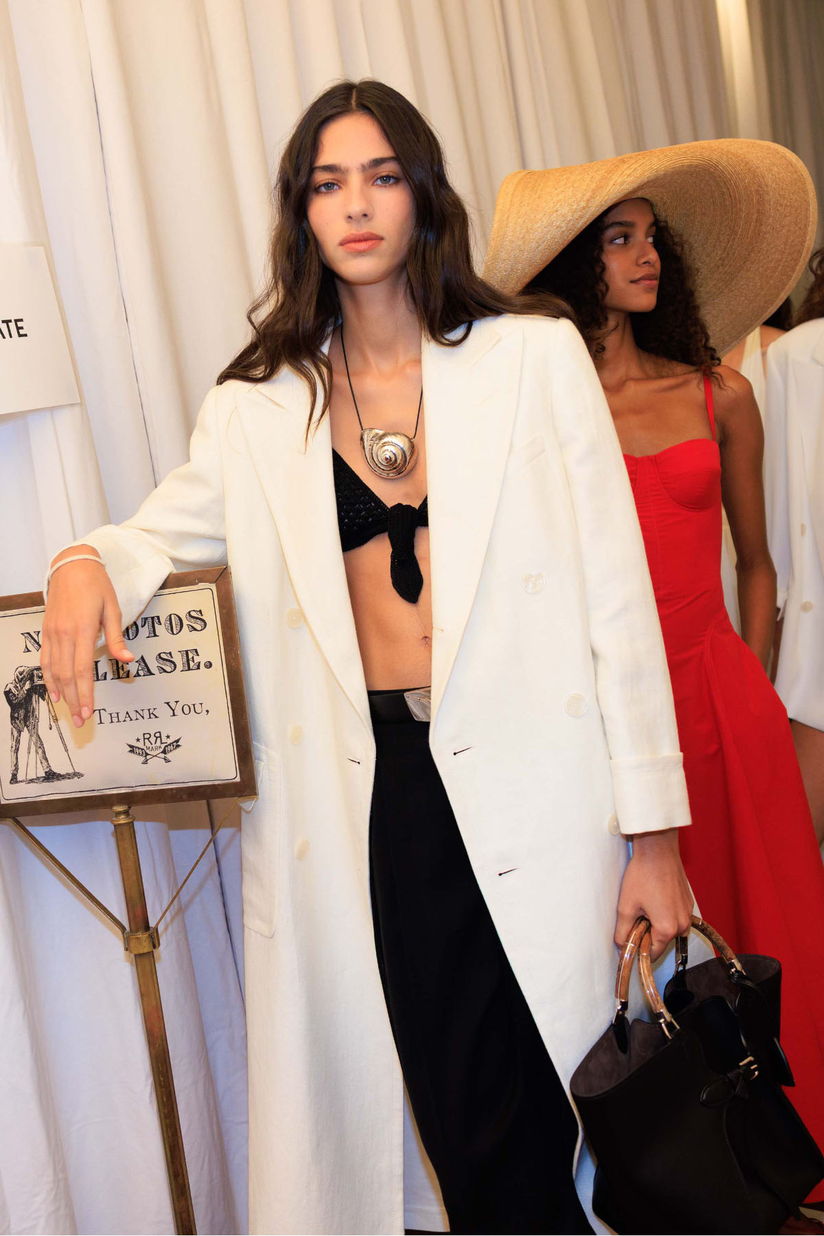 Za kulisami pokazu na wiosnę 2026 Ralph Lauren modelki w eleganckich stylizacjach, jedna w białym płaszczu.