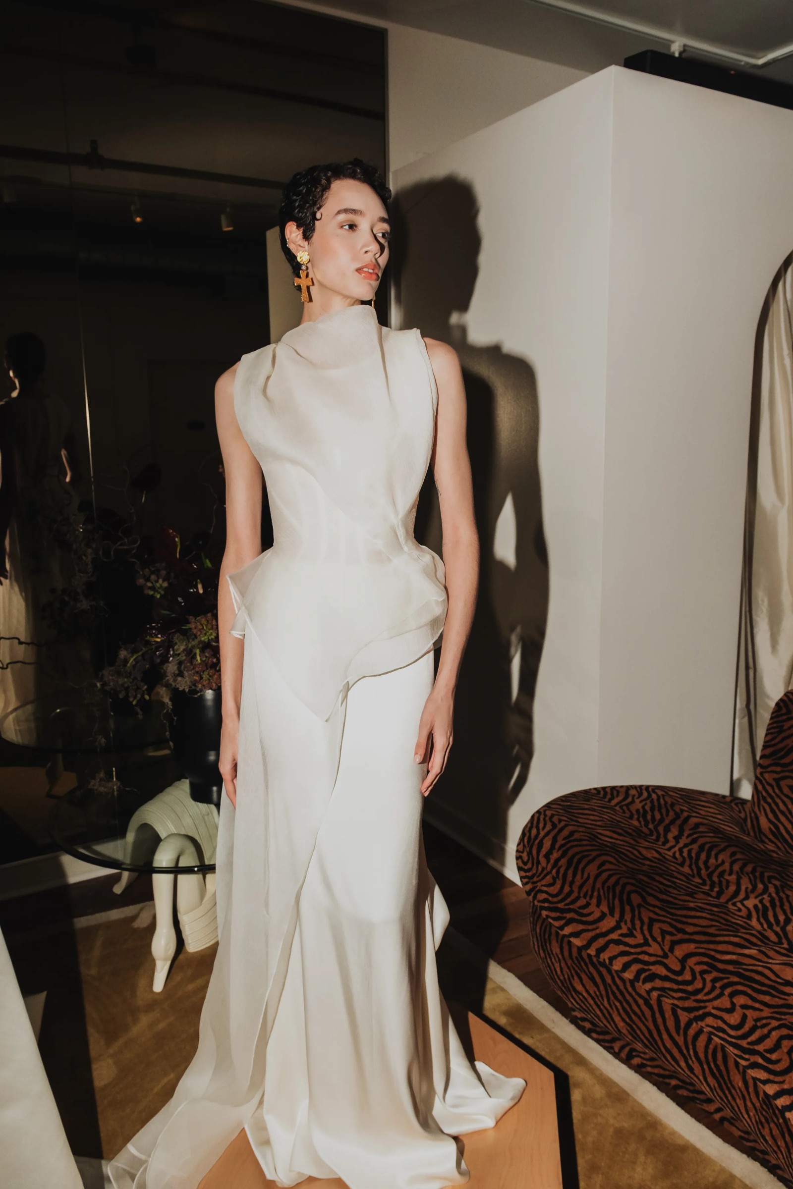 Modelka w eleganckiej sukni ślubnej od sept bridal stoi na tle nowoczesnego wnętrza.