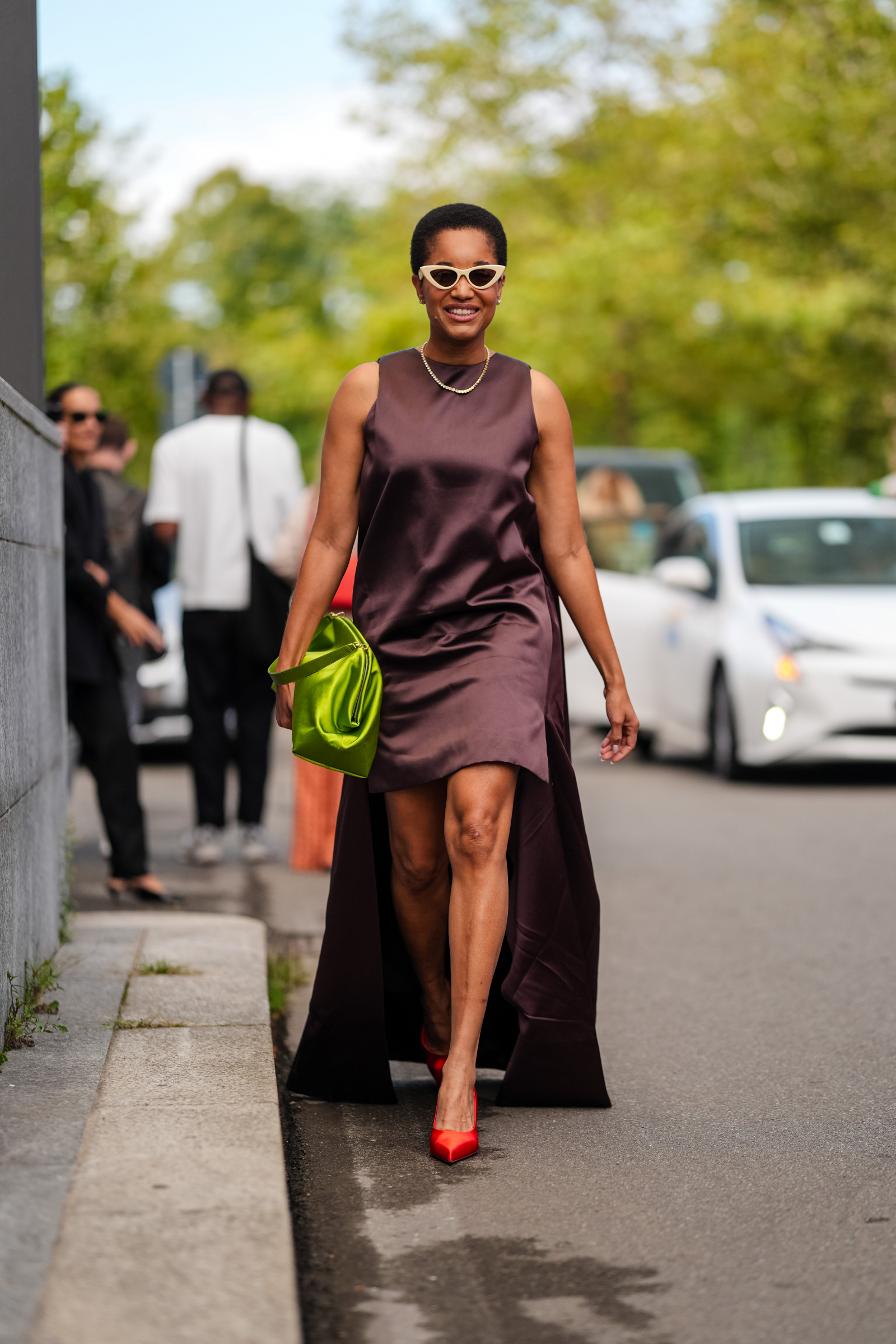 Tamu McPherson brązową minisukienkę z połyskującej tafty nosi z pomidorowymi satynowymi szpilkai w stylu Carrie Bradshaw (Fot. Edward Berthelot/Getty Images)