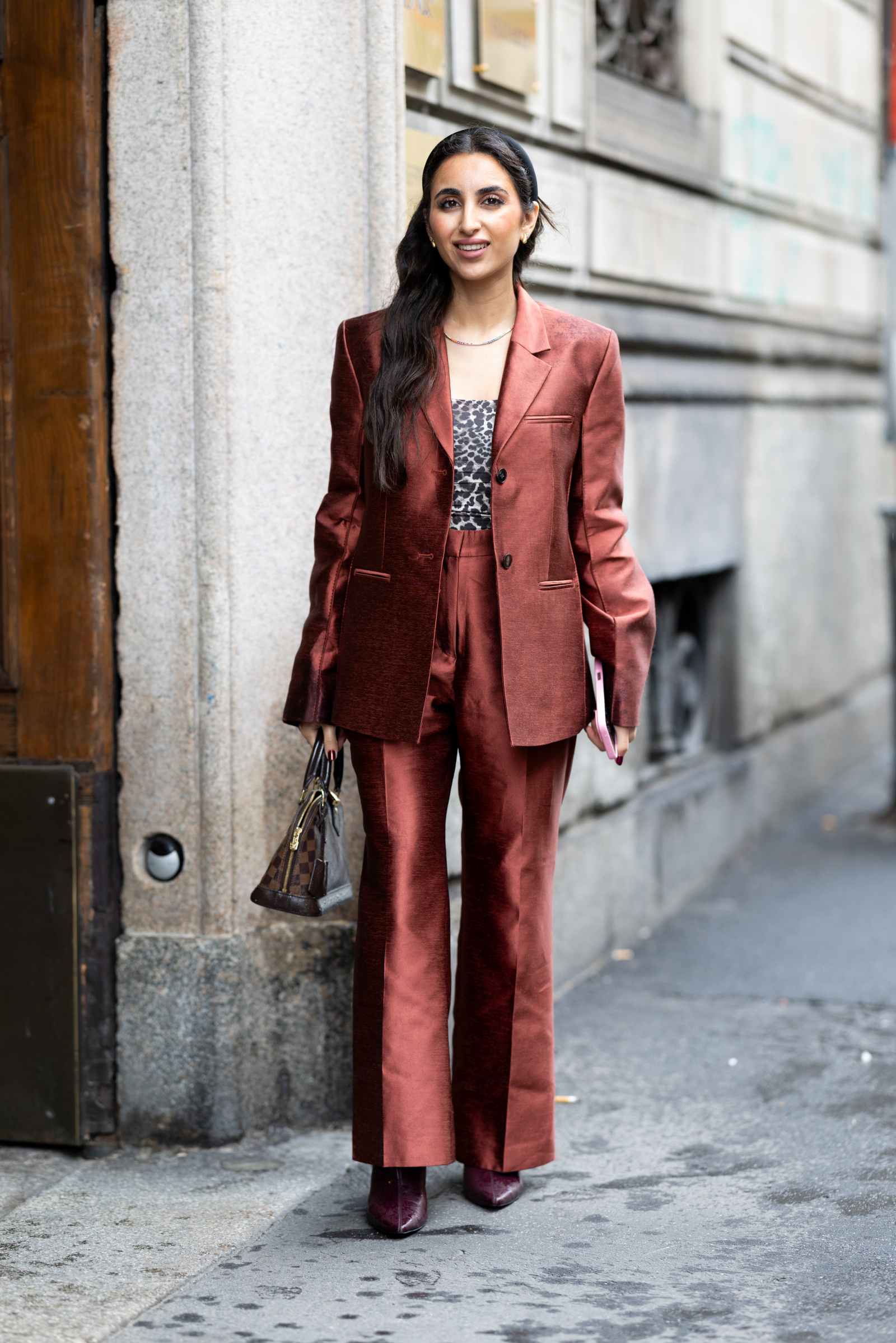 Kobieta w miedzianych spodniach dzwonach oraz burgundowych botkach prezentuje elegancką stylizację na ulicy.