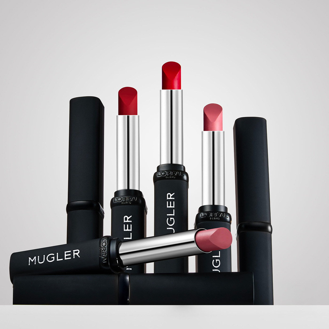 Szminki Mugler w różnych odcieniach na tle białym, z logo L'Oreal Paris na opakowaniu.