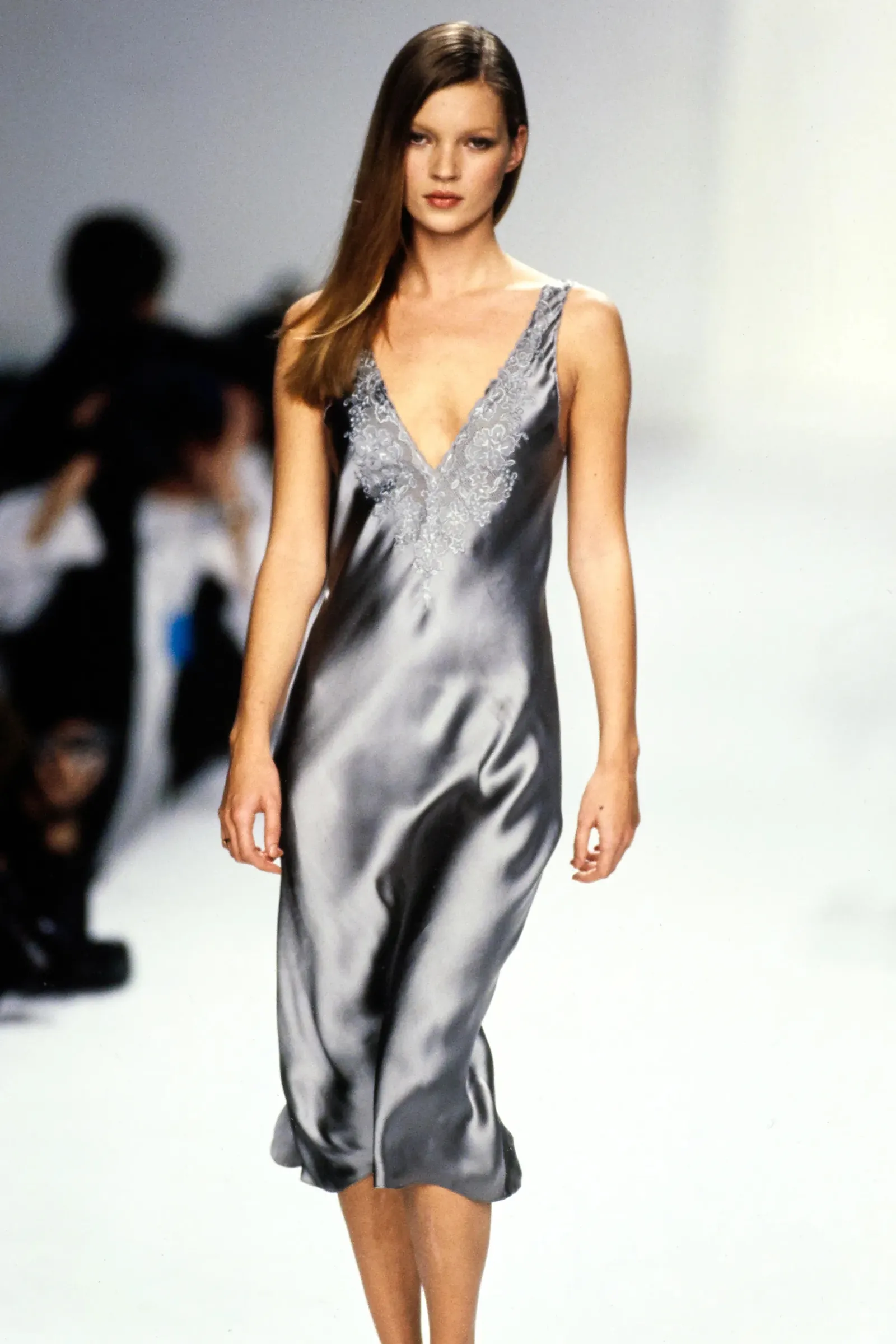 Kate Moss w srebrnej slip dress z 1993 roku, na wybiegu, z eleganckim dekoltem i zdobieniami.