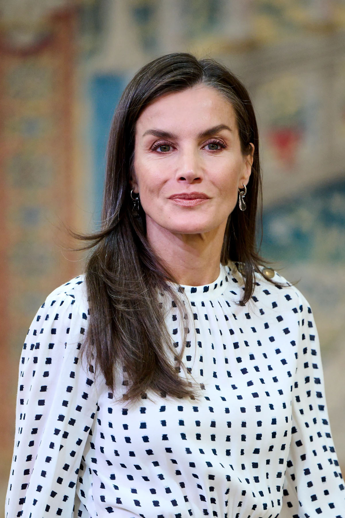 Królowa Letycja w eleganckiej sukience w groszki, z długimi włosami i subtelnym makijażem.