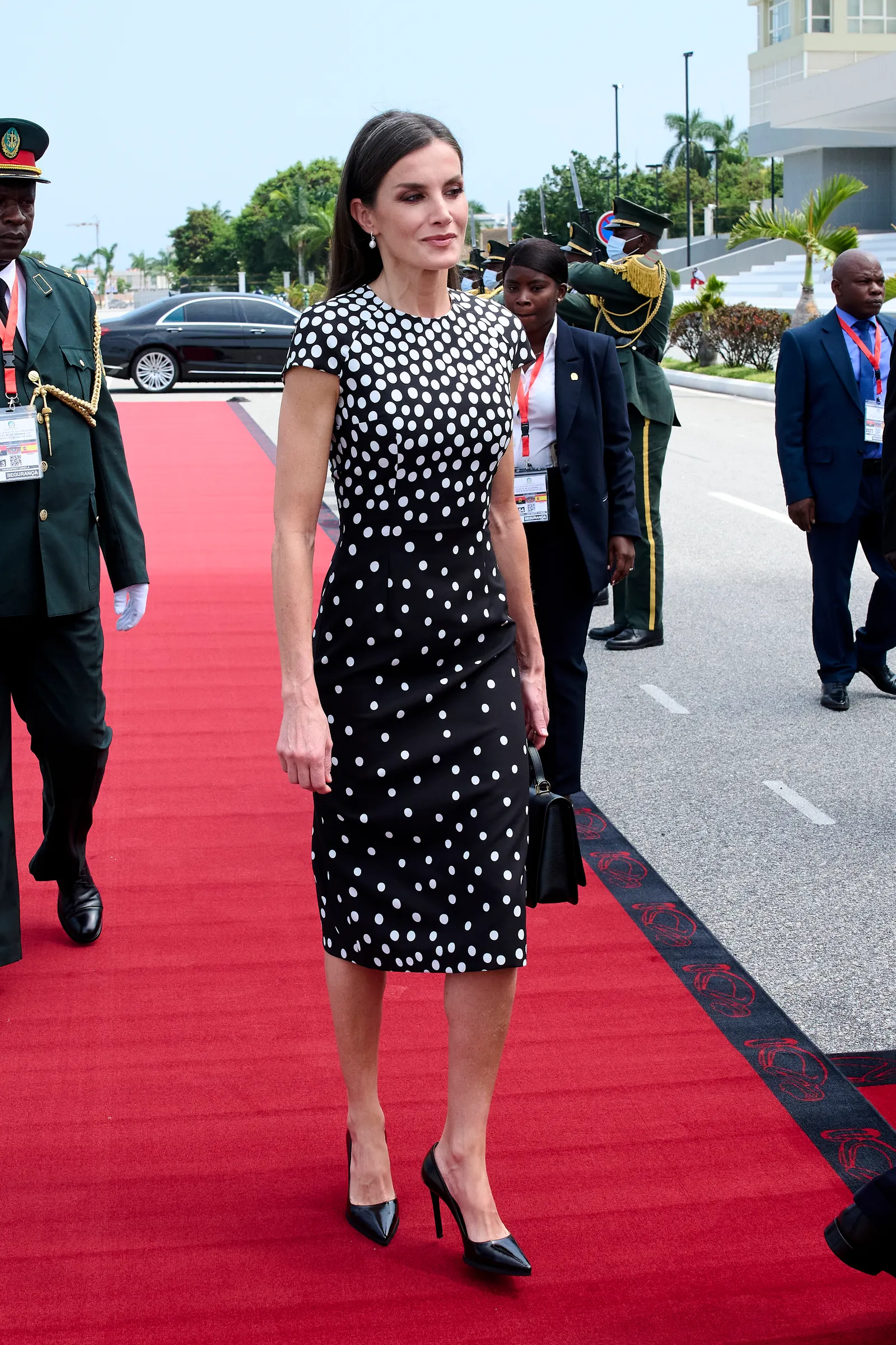 Królowa Letycja w eleganckiej sukience w groszki, spaceruje po czerwonym dywanie.
