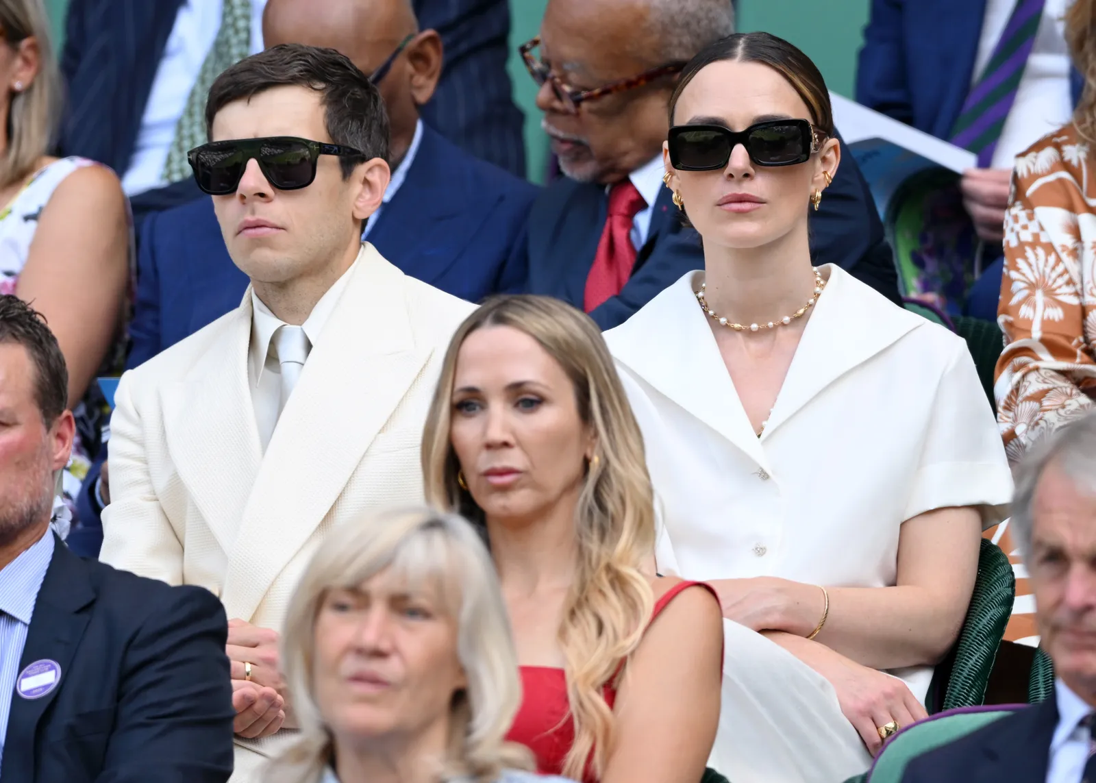 Keira Knightley w jasnej stylizacji uzupełnionej okularami przeciwsłonecznymi, złotymi kolczykami kreolkami i dopasowanymi małymi nausznicami (Fot. Karwai Tang/Getty Images)